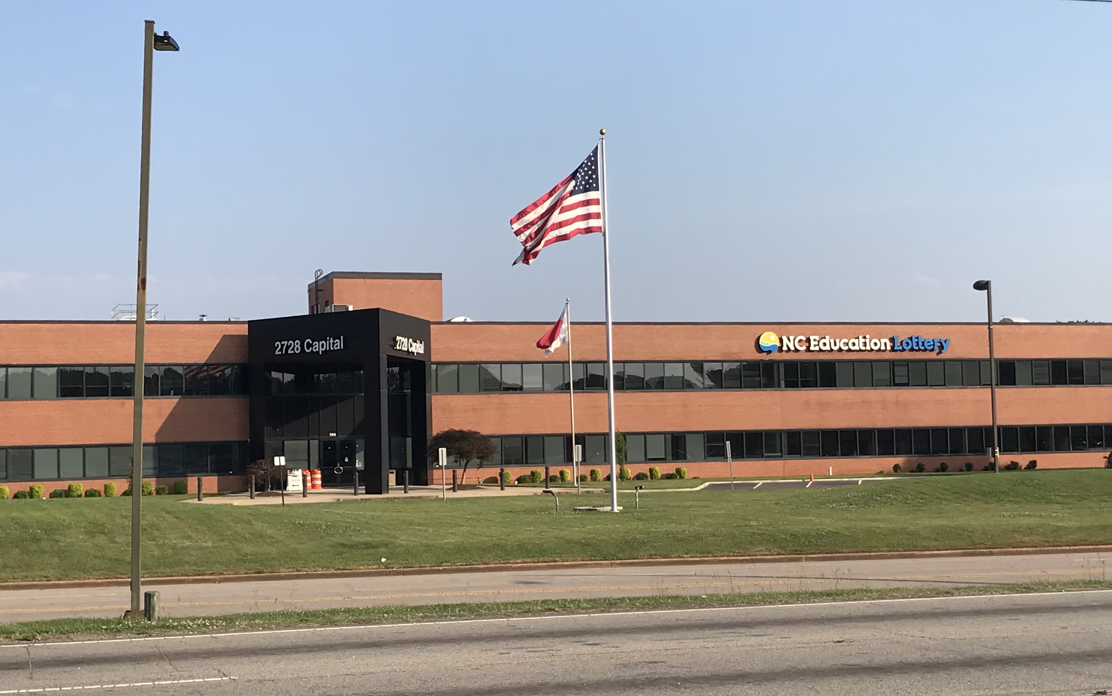 Brick office building with NC Education Lottery sign and two flagpoles out front.