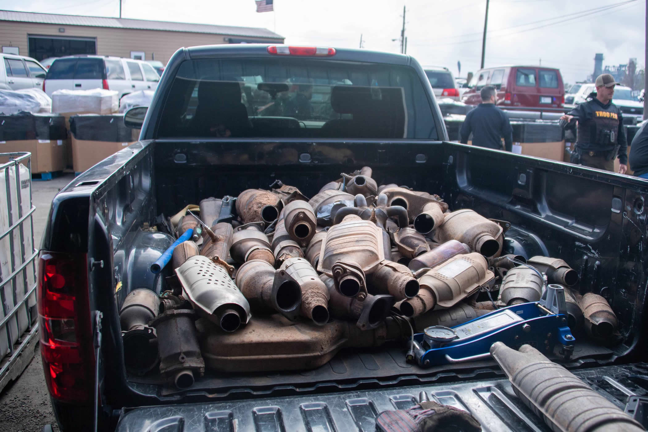 A pickup truck bed piled high with dozens of used catalytic converters.