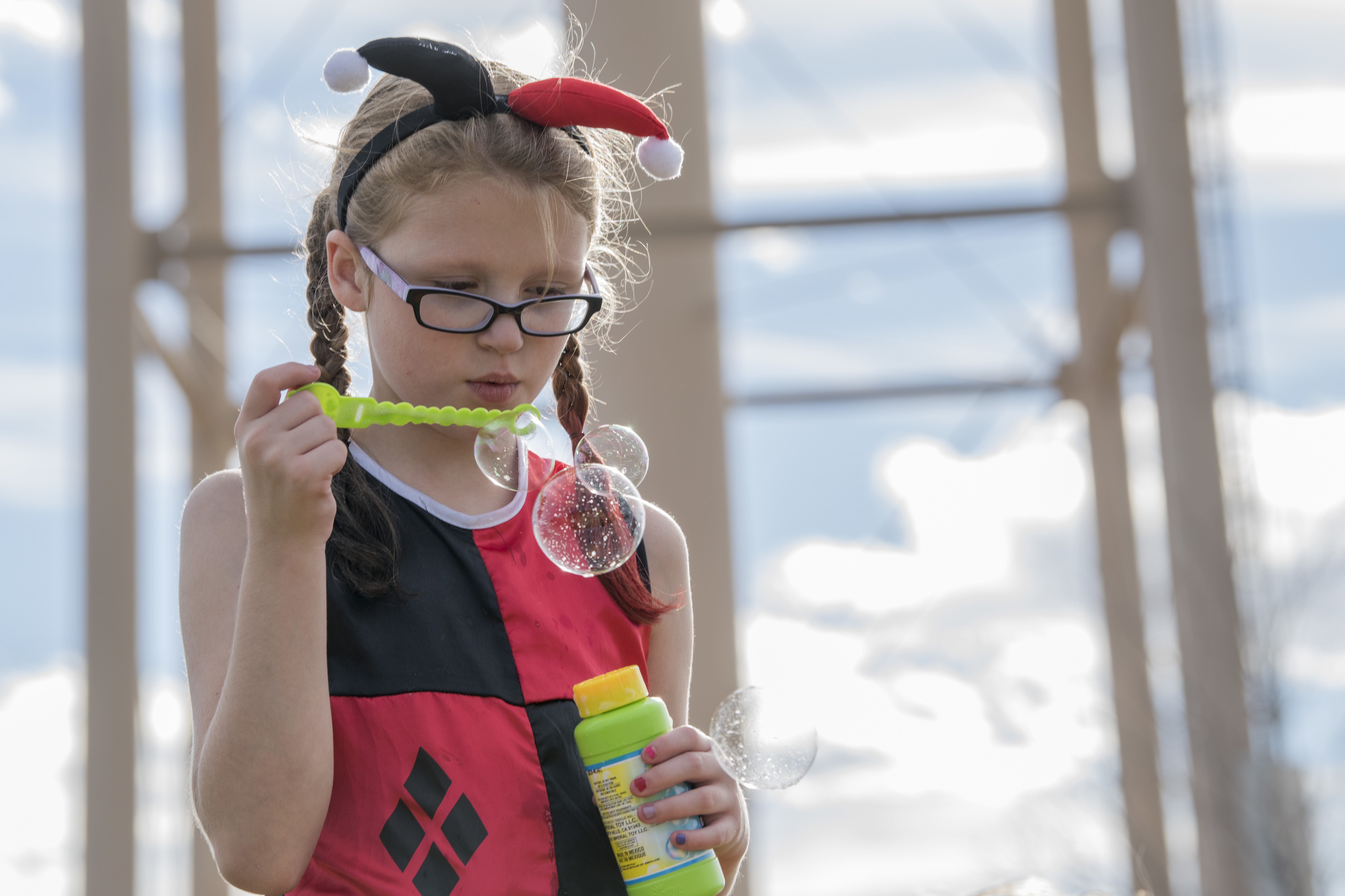 A young girl in a Halloween costume blows bubbles at an outdoor fall festival.