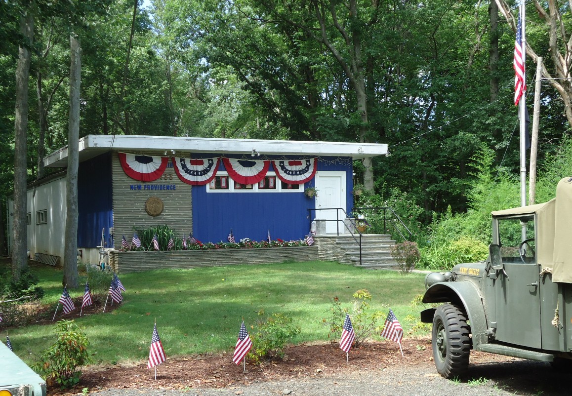 Single-story American Legion post building adorned with red, white, and blue patriotic bunting and small American flags.