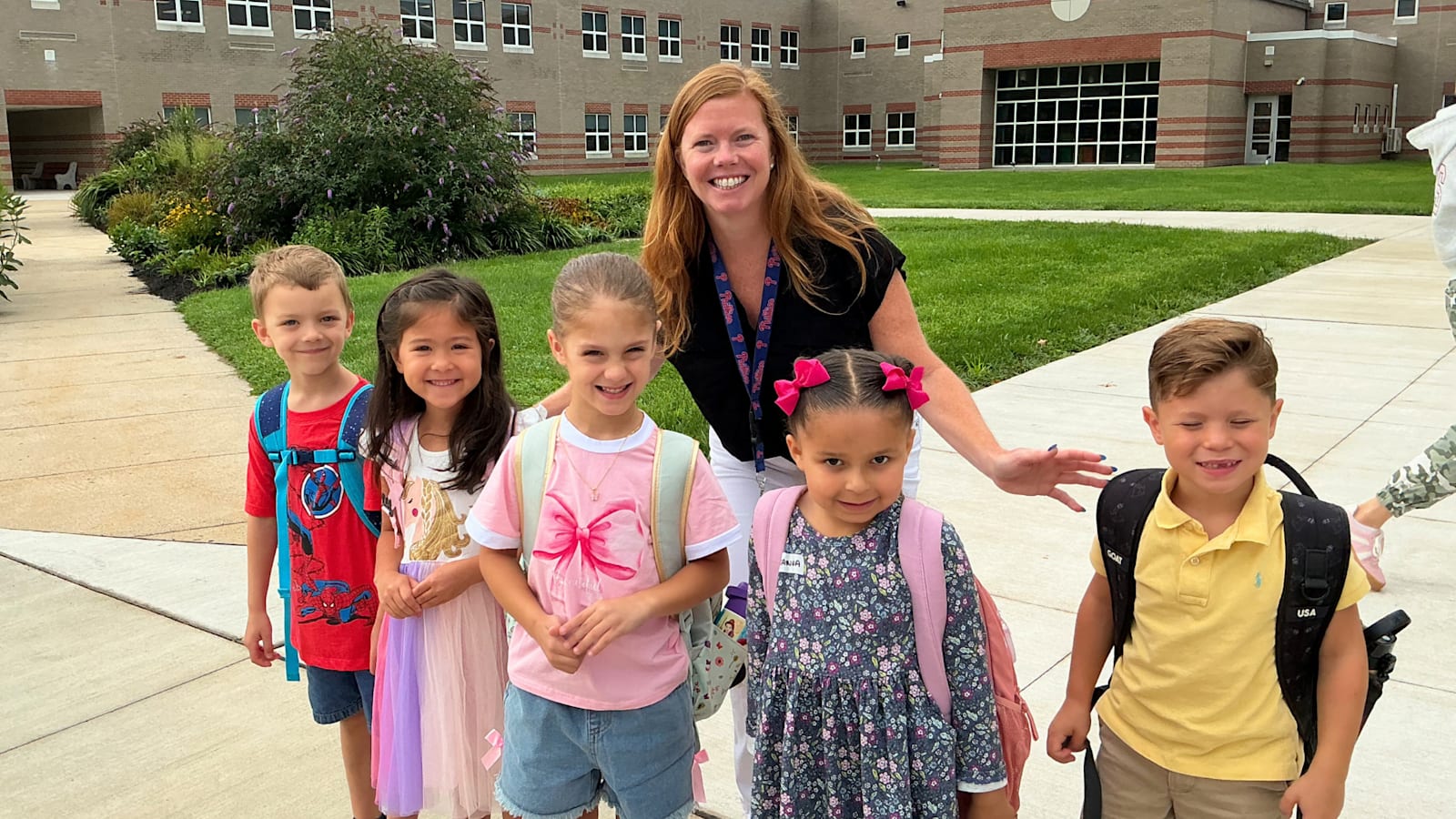 A teacher stands with five students wearing backpacks outside Cold Spring Elementary School.