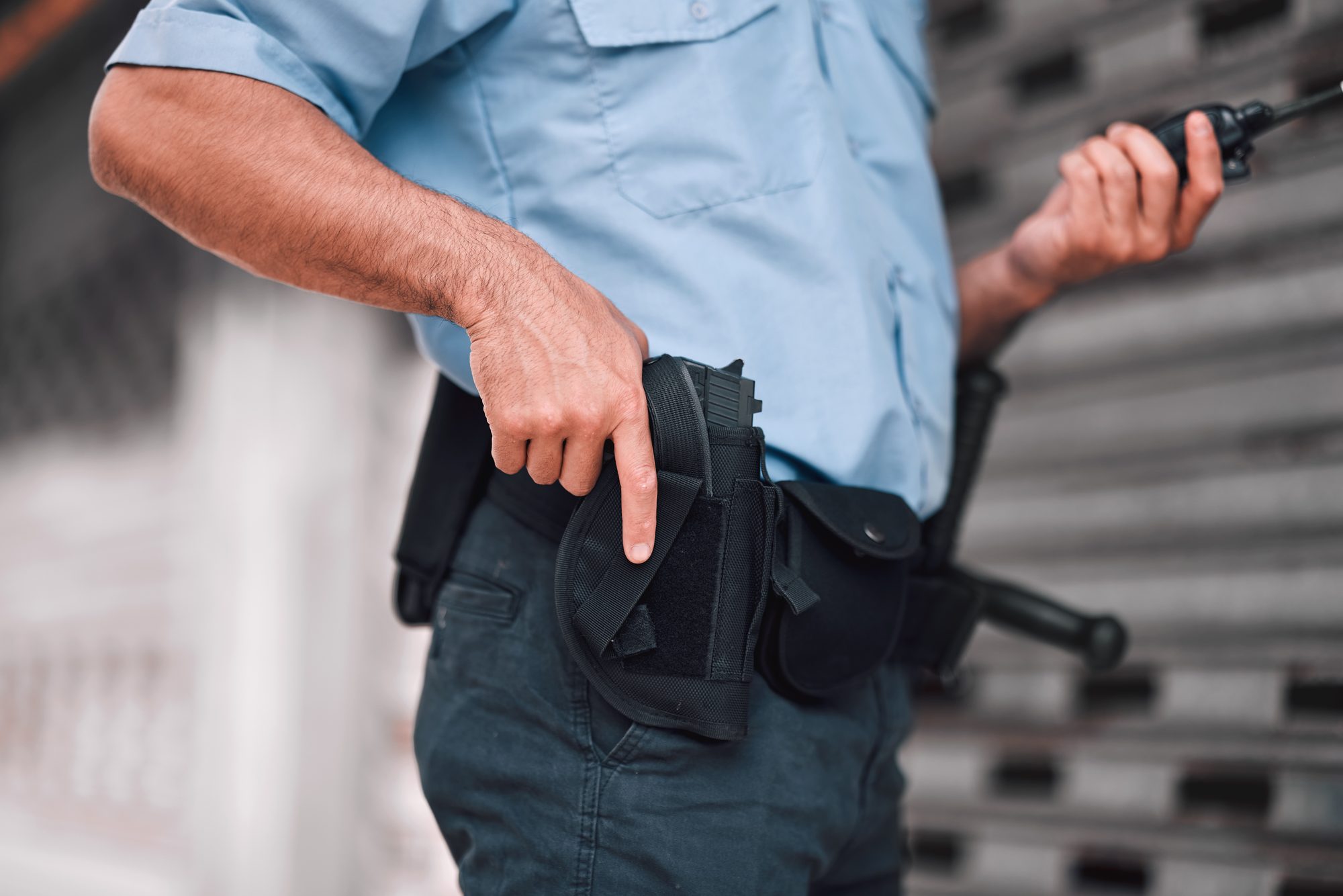 Closeup, law or police officer with a gun, safety or career with legal enforcement, armed or crime. Zoom, man or security guard with service weapon, protection or danger with walkie talkie or uniform