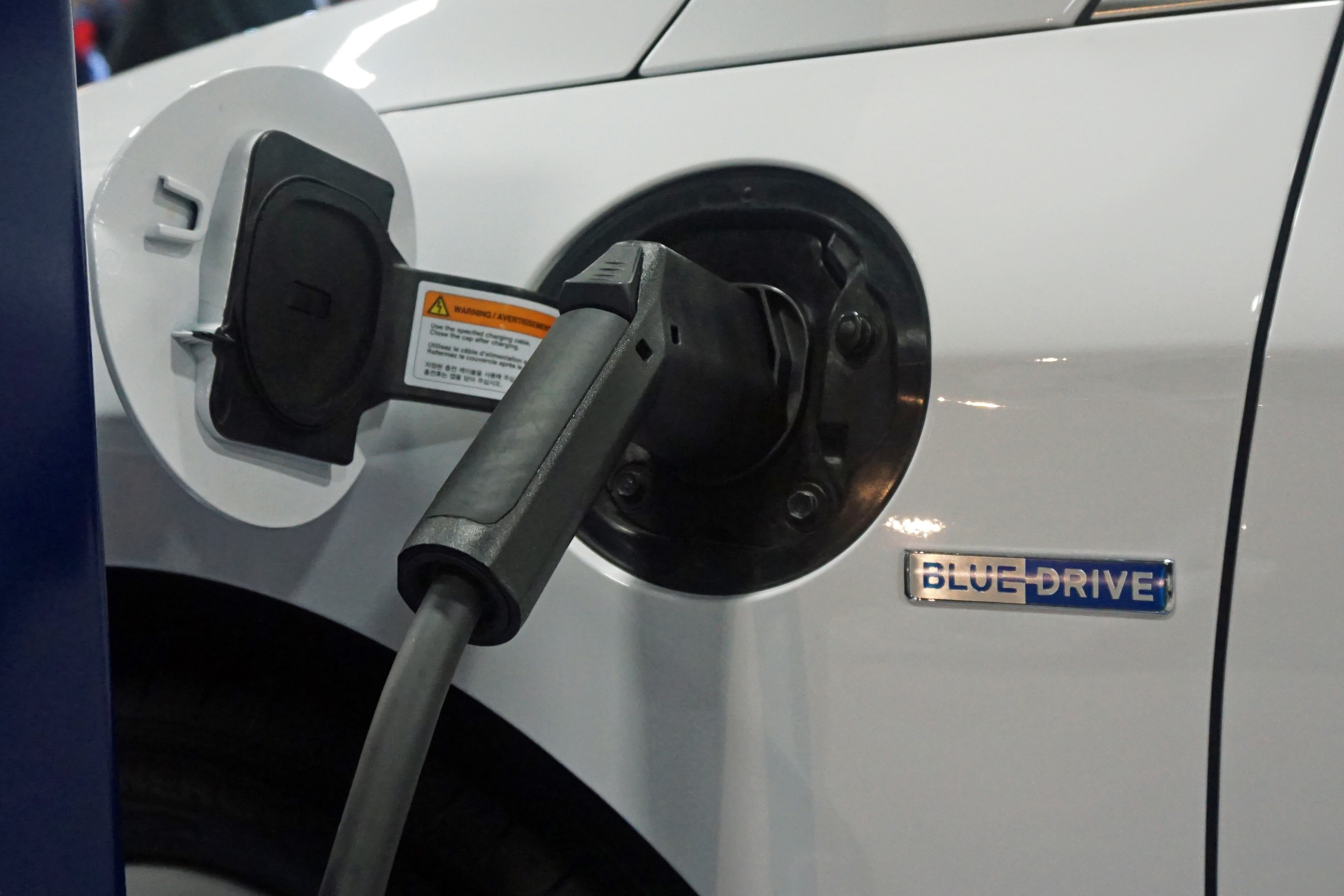 Charging cable inserted into the port of a white plug-in hybrid car.