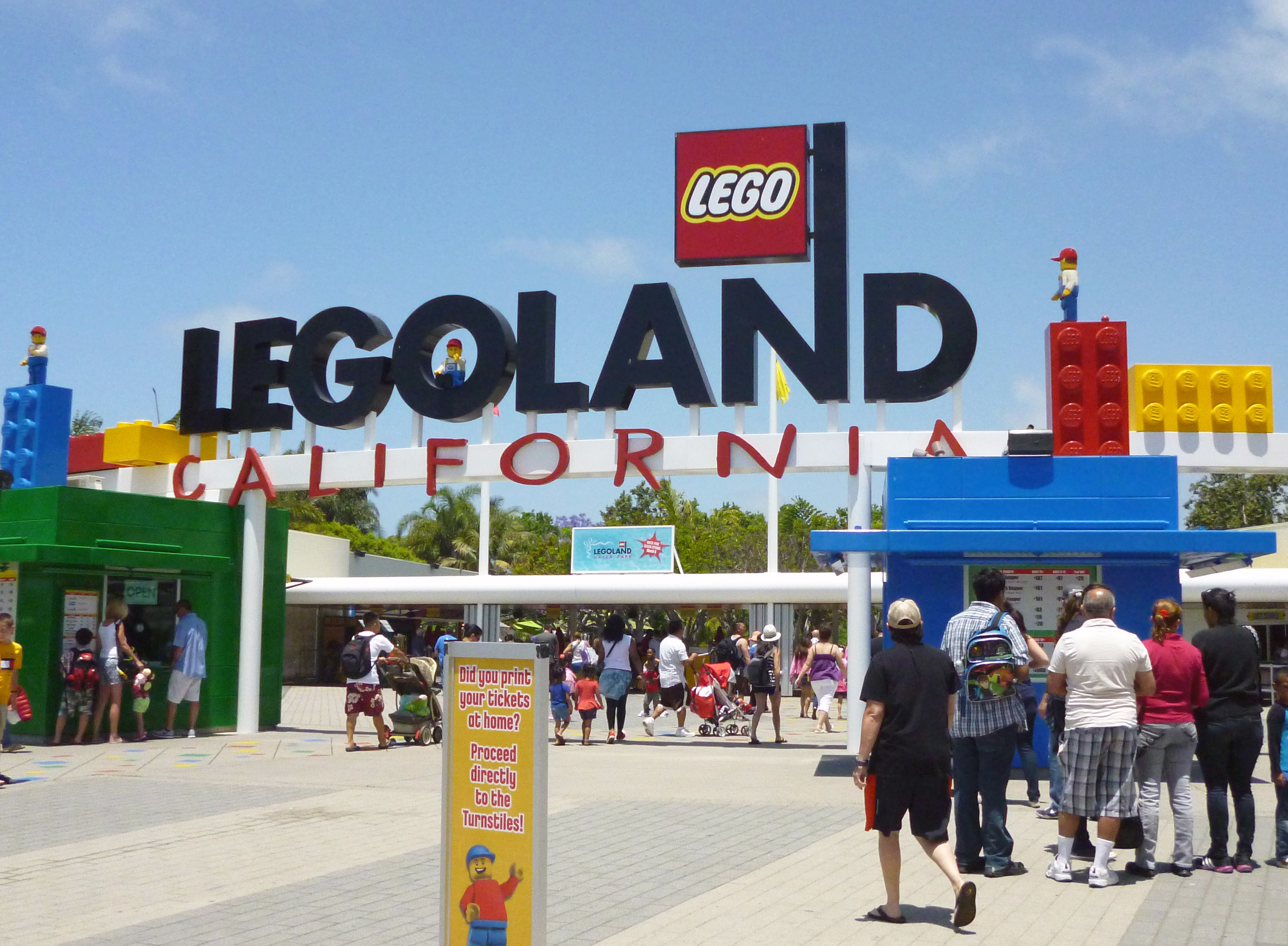 Entrance gate and sign of LEGOLAND California theme park with visitors approaching.