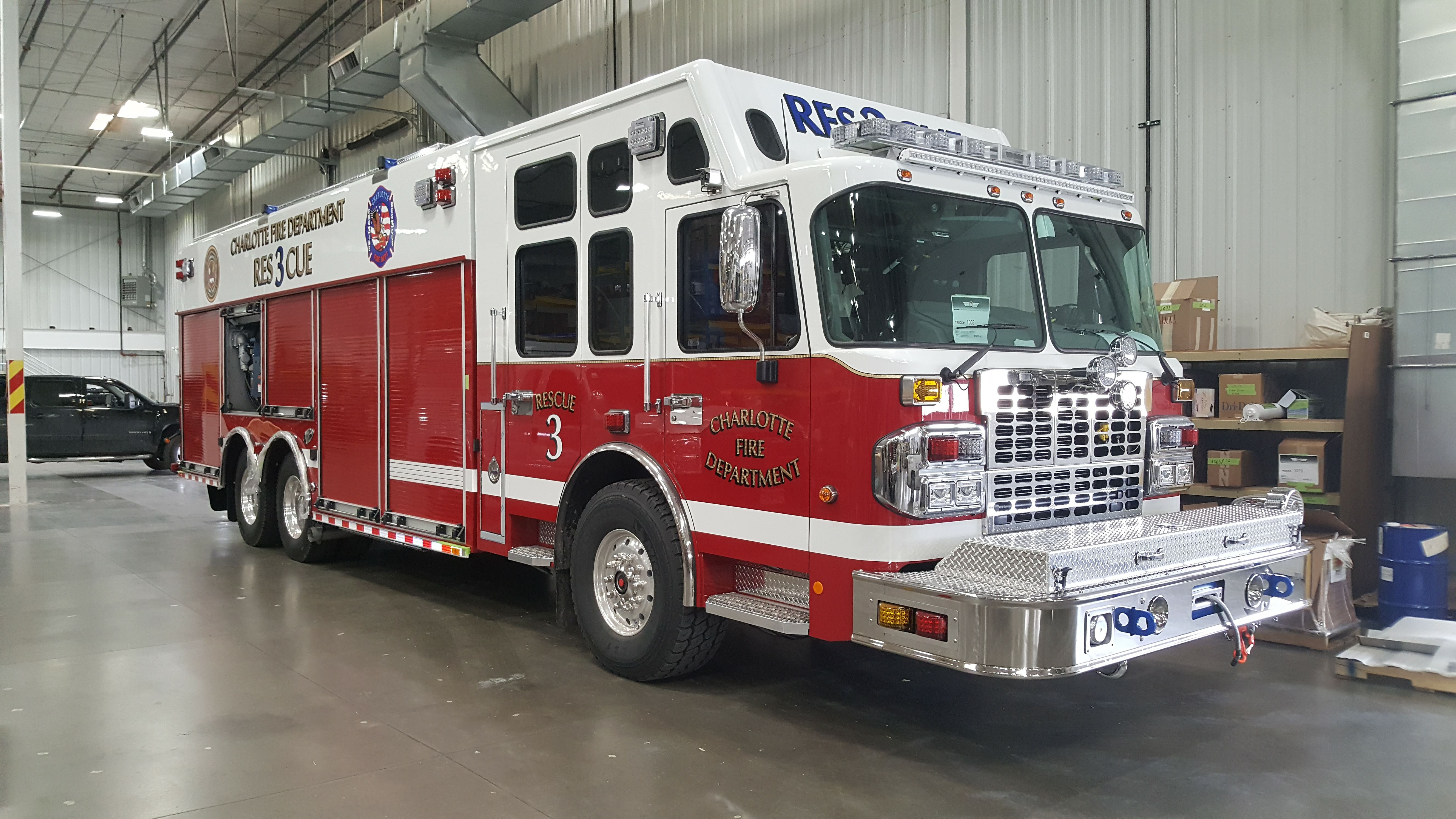 Red and white fire department heavy rescue truck labeled Rescue 3 parked inside a facility.