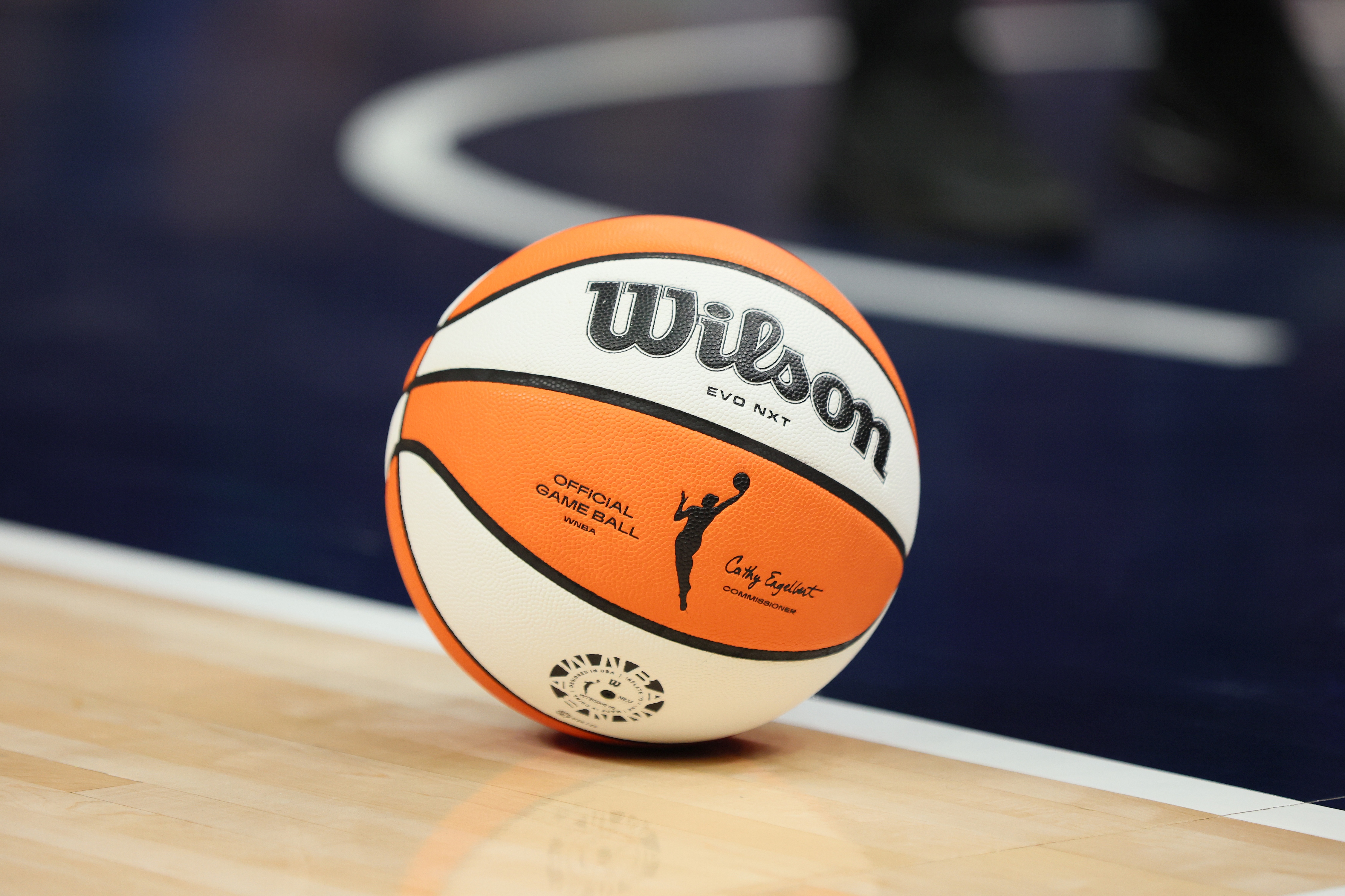 An official WNBA game ball resting on a hardwood basketball court floor.