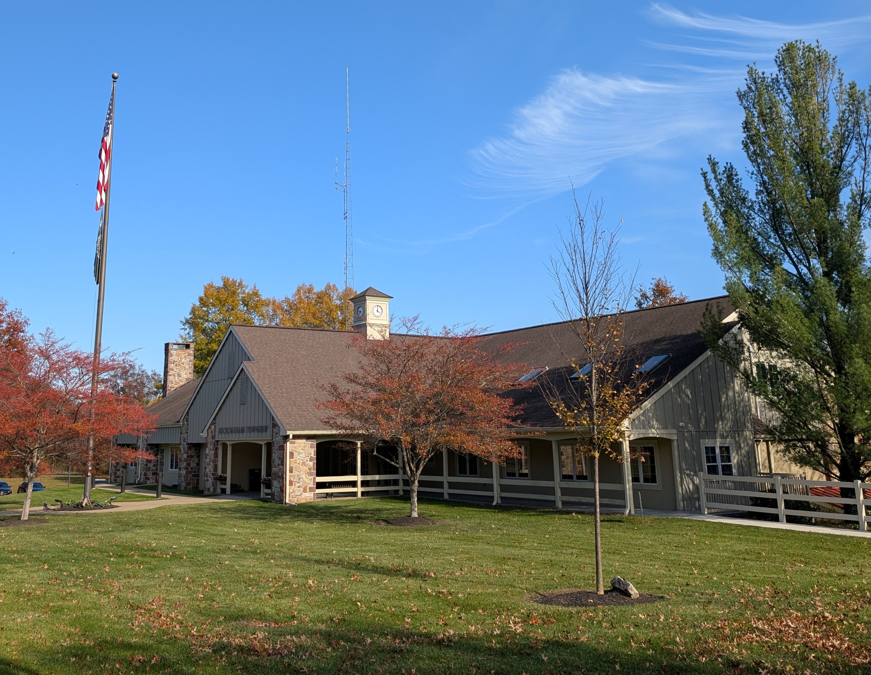 Municipal building with clock tower, stone exterior, and American flag on a tall flagpole.