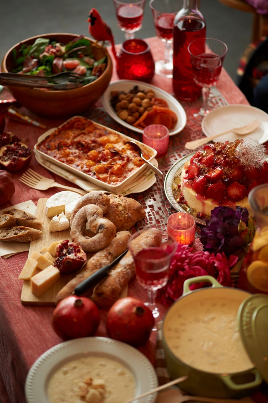 A vibrant dinner table setup featuring Italian dishes, bread, cheese, and a festive atmosphere.