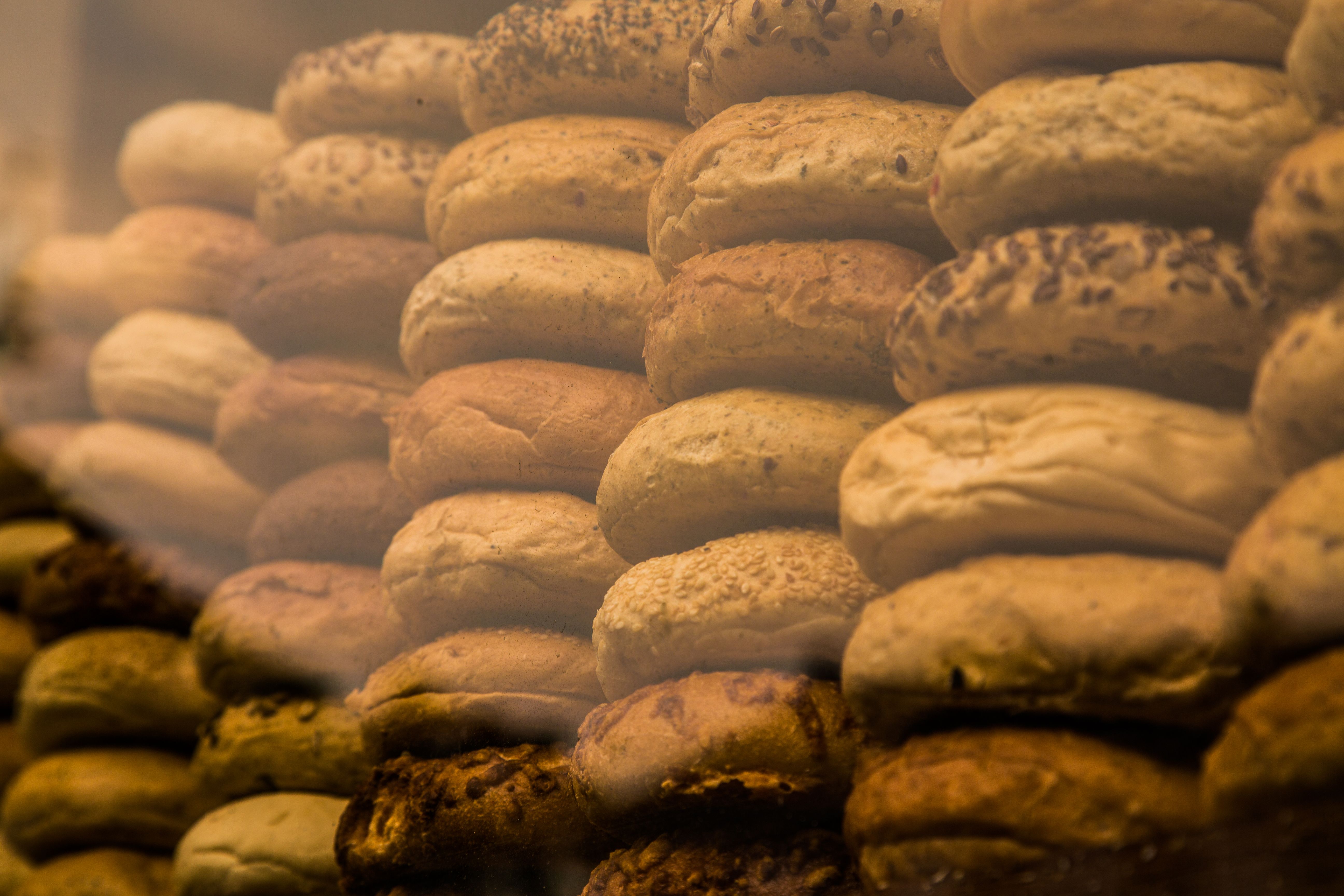 Dozens of sesame and plain bagels stacked in rows in a display case.