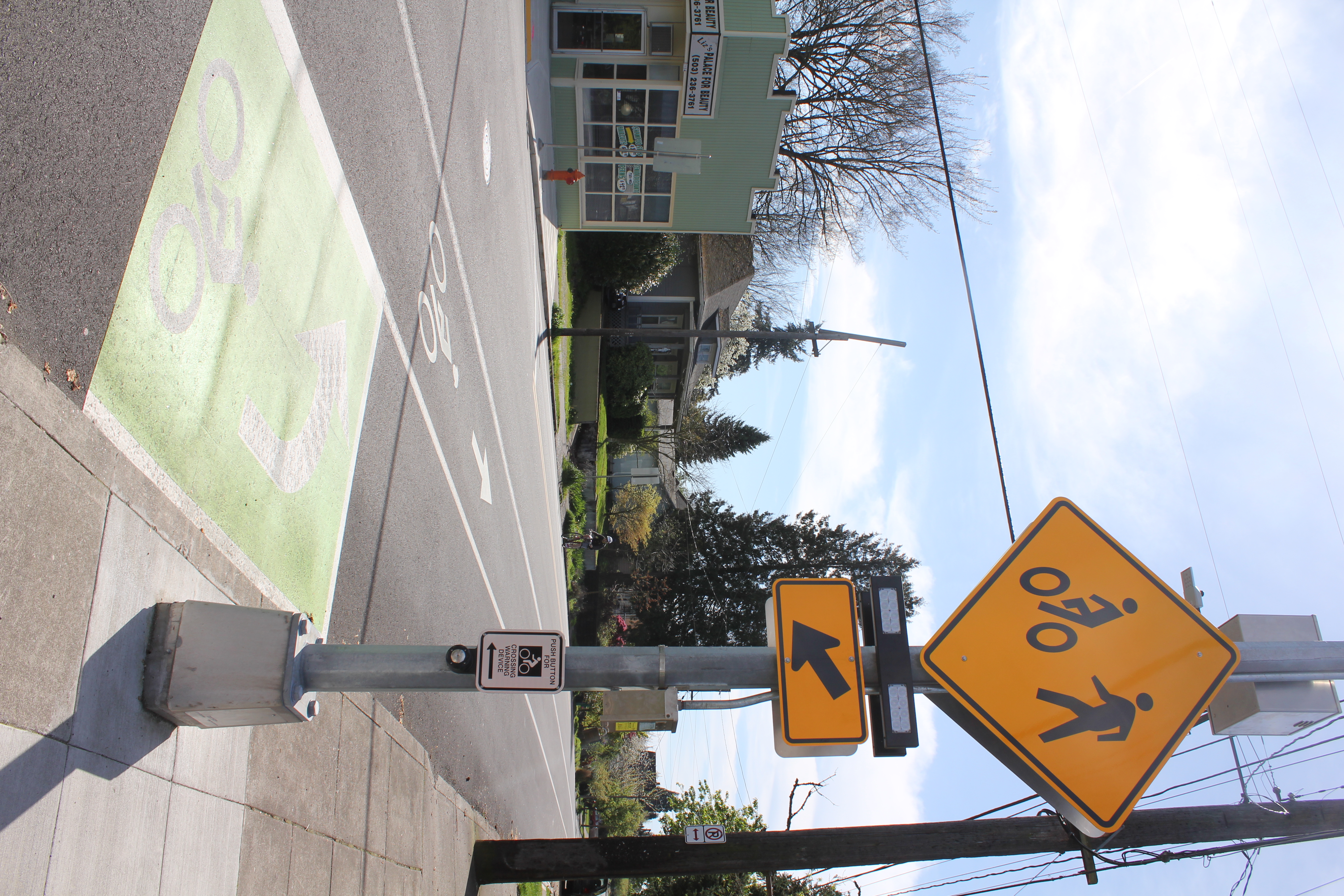 Yellow RRFB crosswalk sign and push-button mounted on a pole at a street crossing.