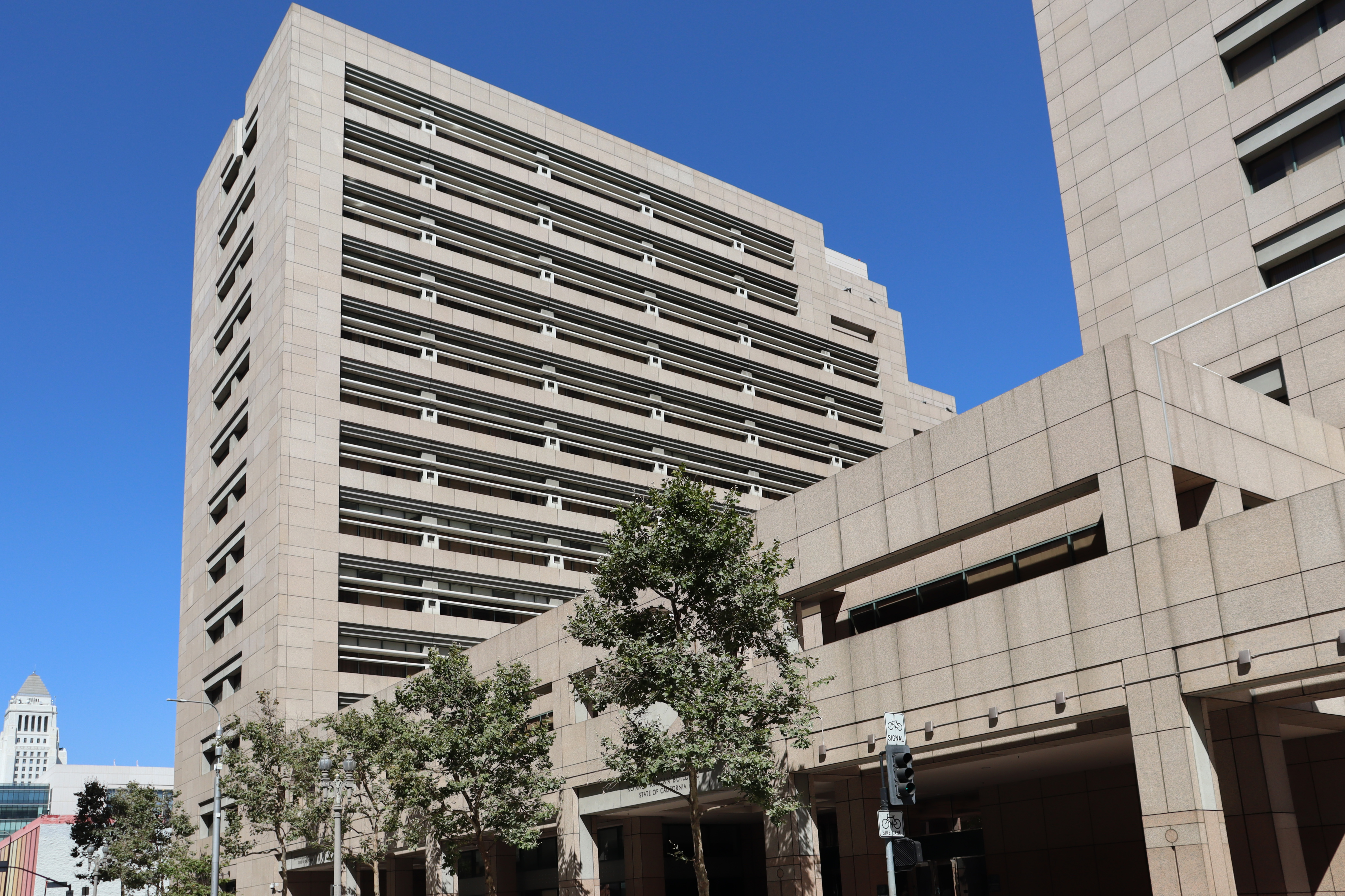 Tall brutalist concrete office building with trees along the sidewalk in downtown Los Angeles.