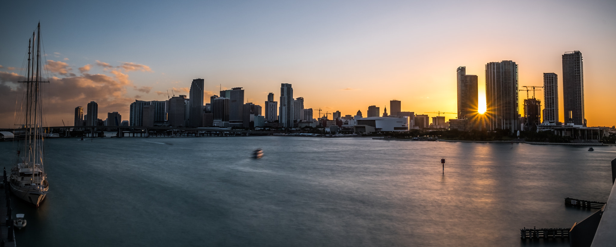 Miami downtown skyline glows at sunset, reflected over Biscayne Bay.