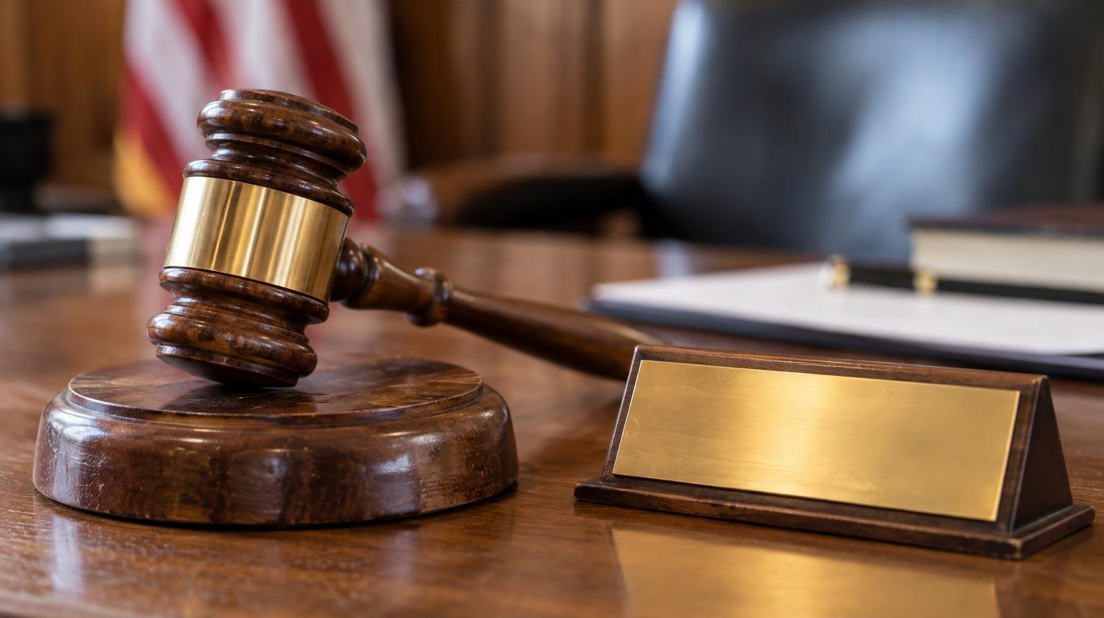 Wooden judge's gavel resting on its sound block on a polished surface.