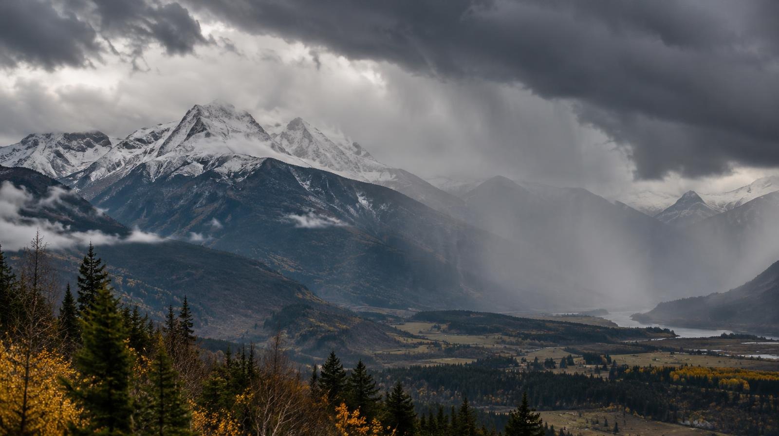 Dark storm clouds over snow-dusted mountain peaks with rain falling in the valley.