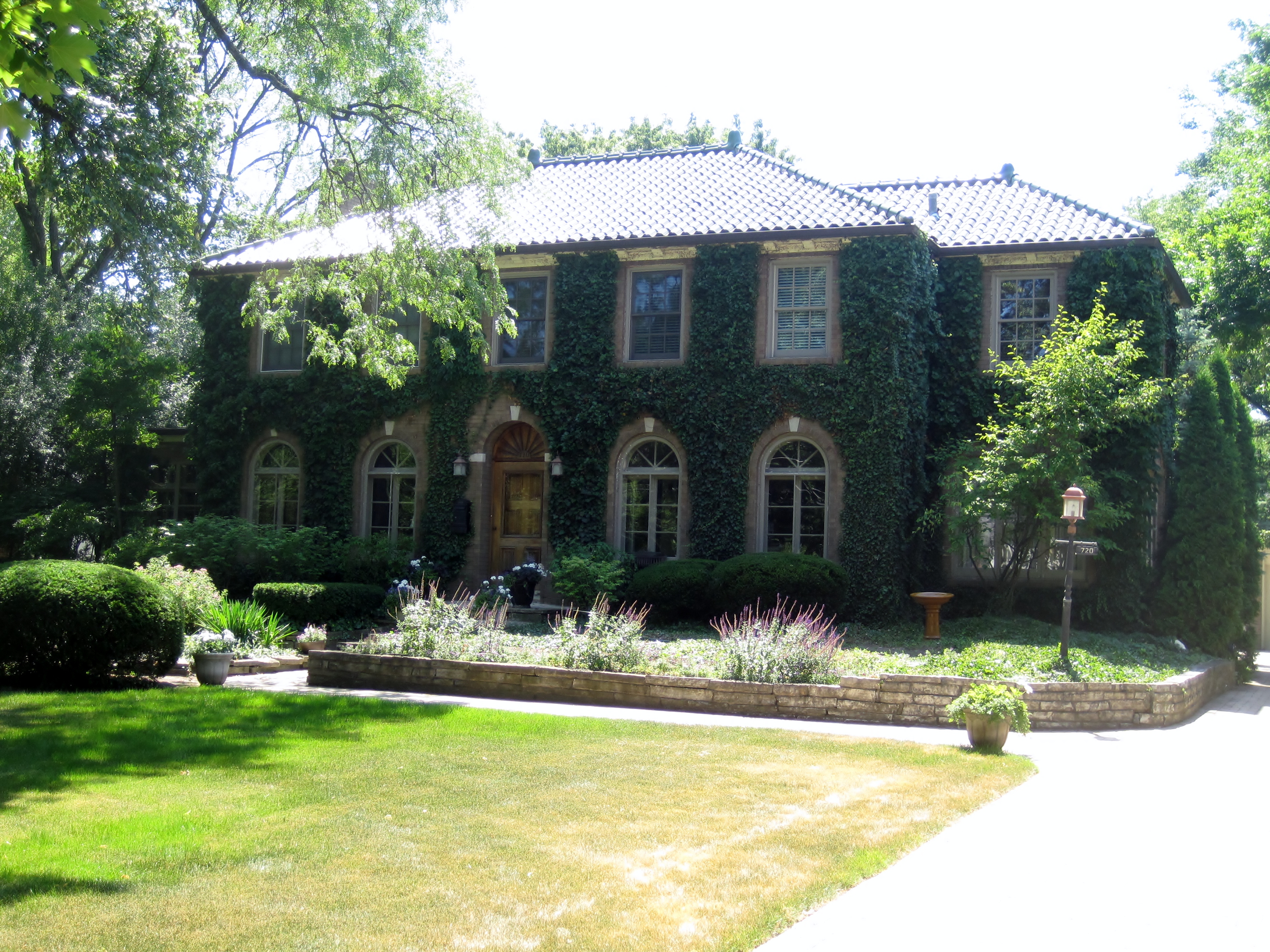 Ivy-covered two-story brick house with arched windows and manicured lawn.