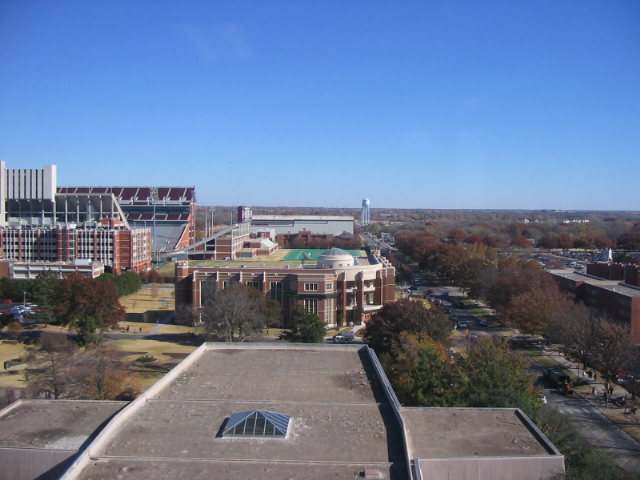Elevated view of a college campus with brick buildings and a large stadium visible in the background.