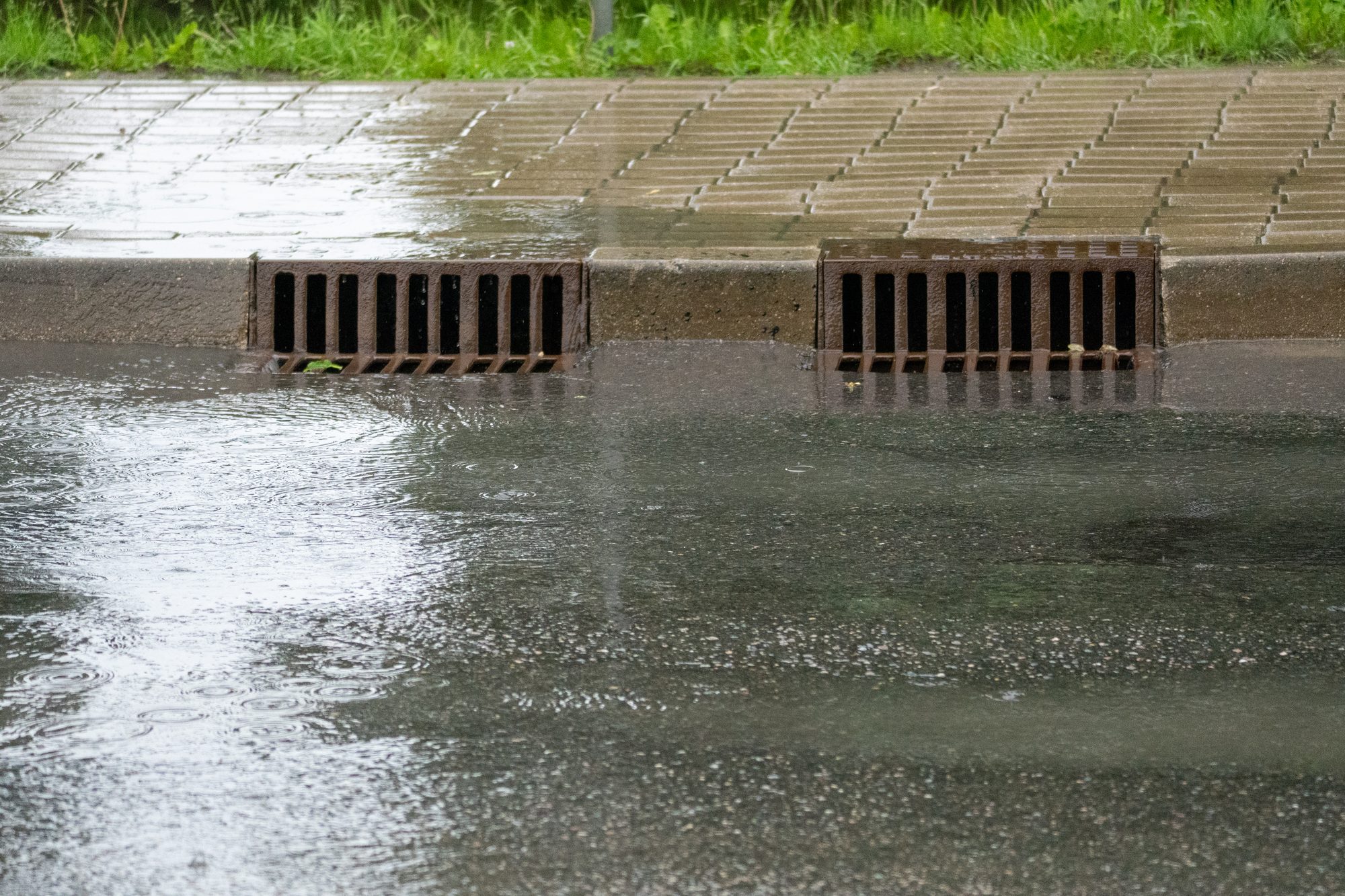 Storm Drains Collecting Rainwater from Flooded Street During Heavy Rain
