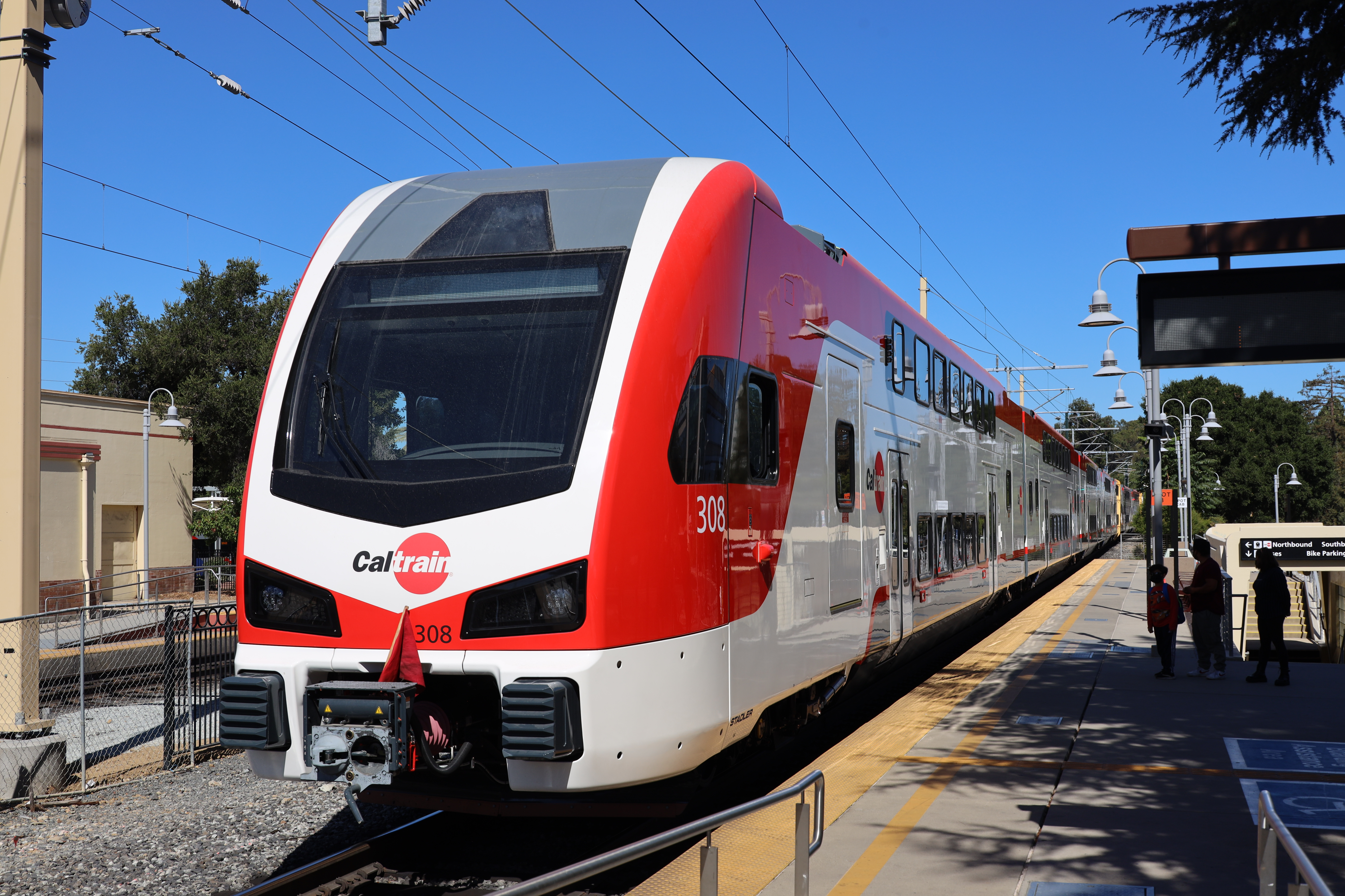 Red and white Caltrain electric train stopped at an outdoor station platform.