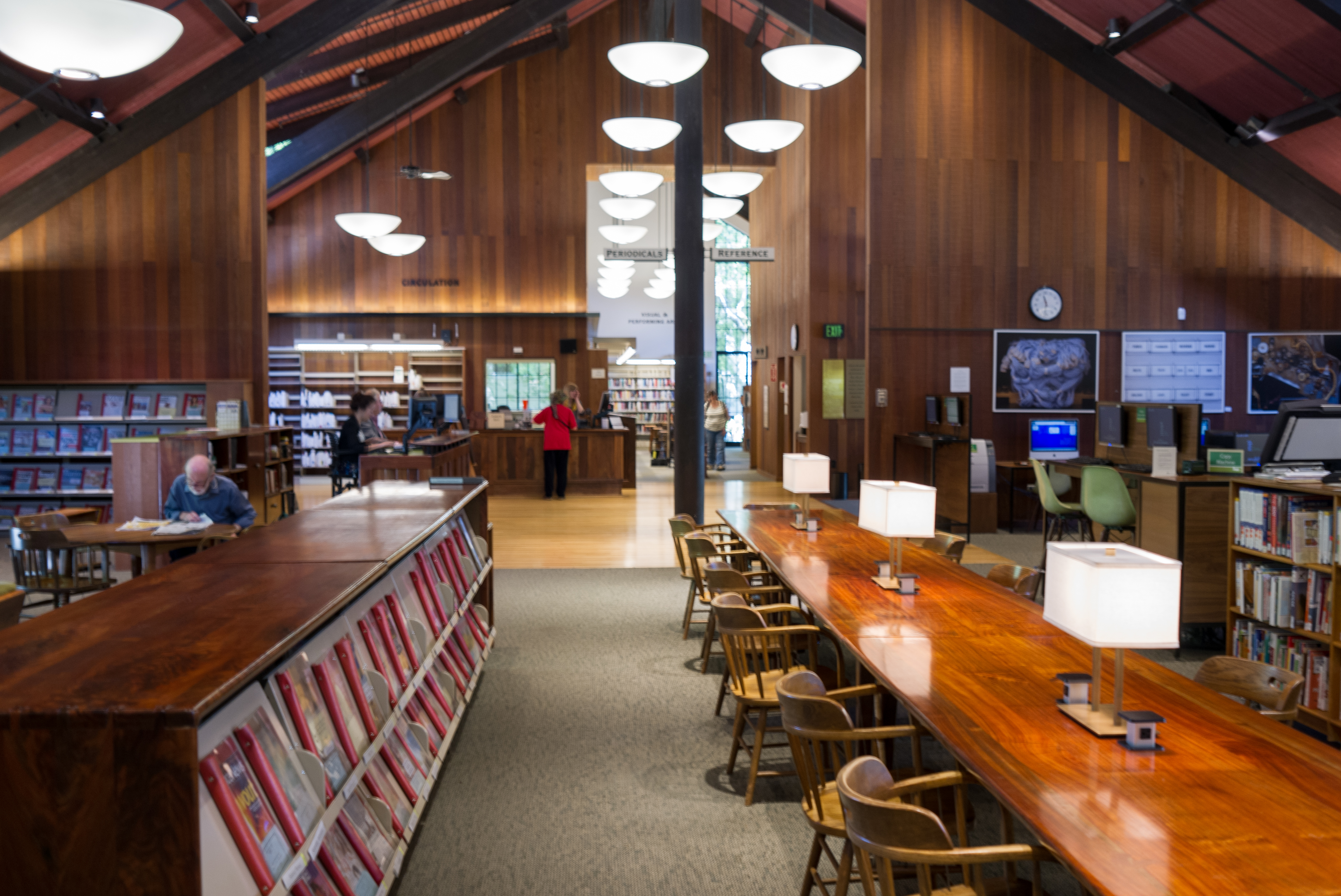Library reading room with a tall wood-paneled A-frame ceiling and long wooden tables.