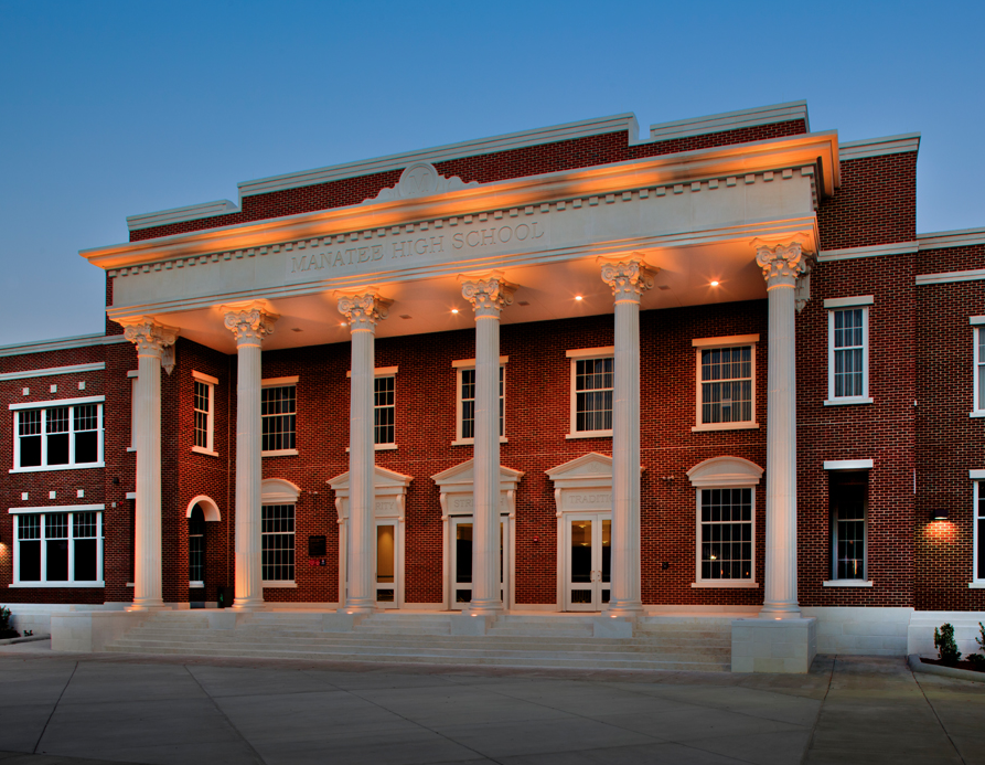 Red brick school building with white columns and school name engraved above the entrance.