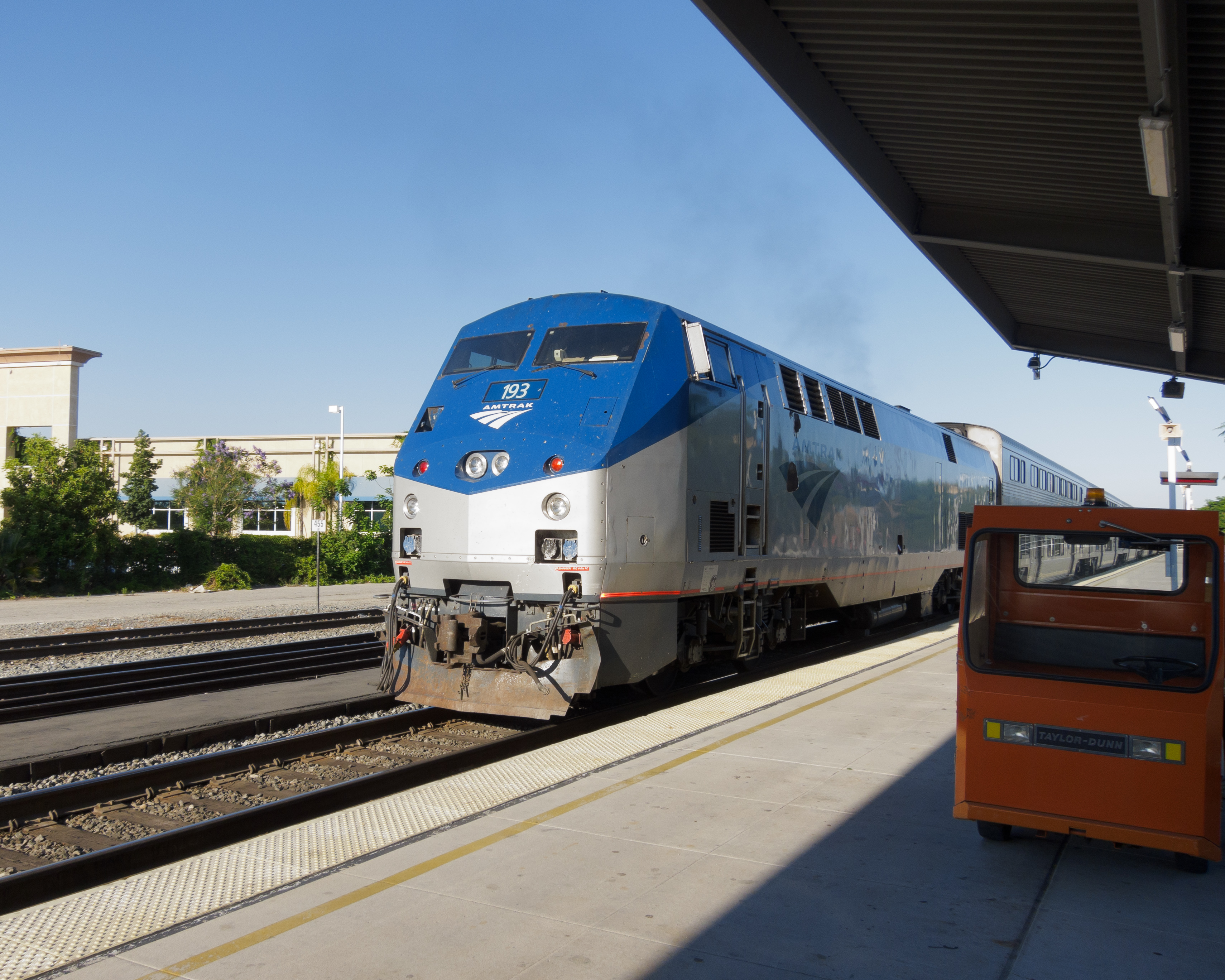 Amtrak locomotive in blue and silver livery pulling away from a covered station platform.