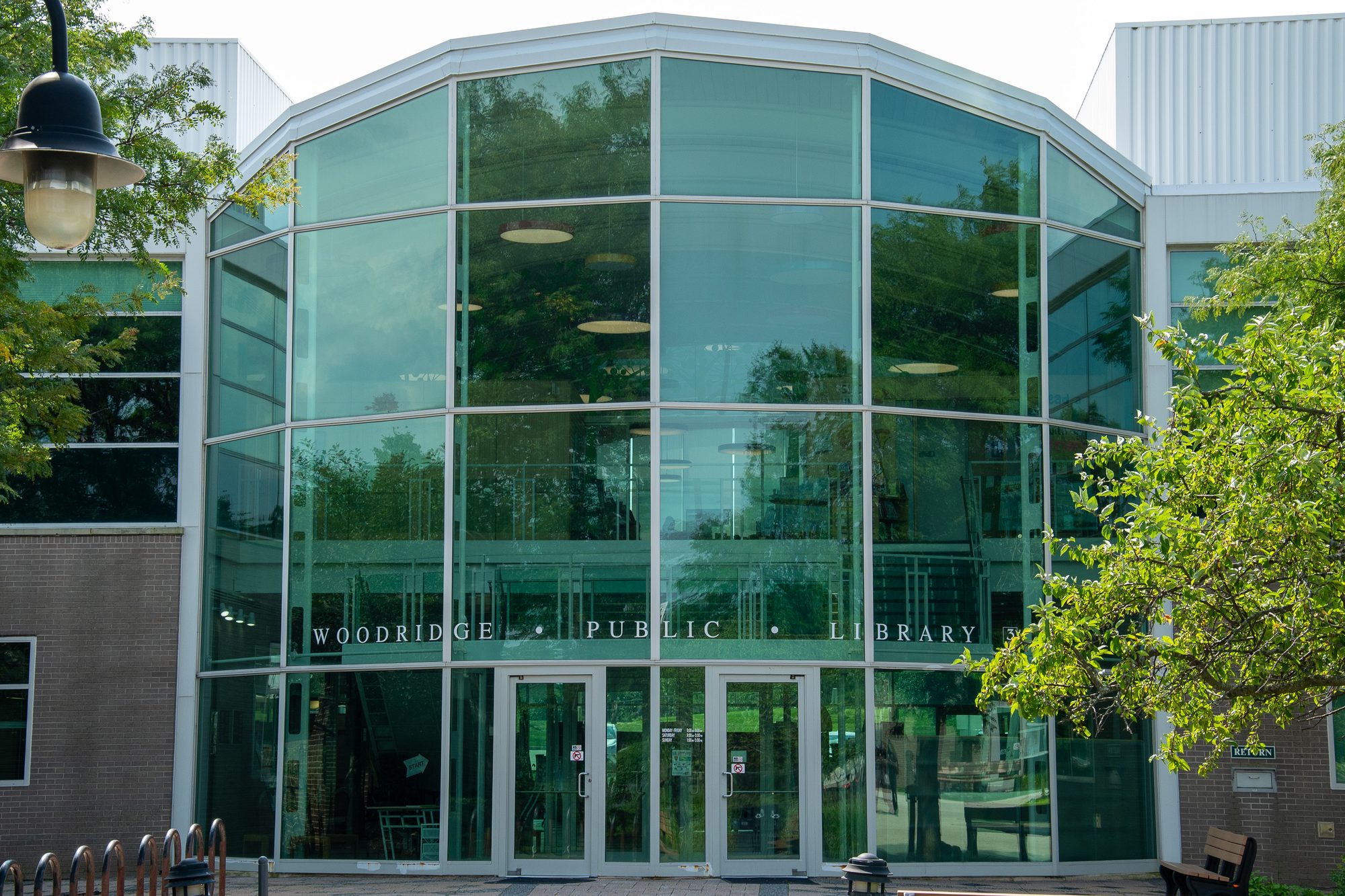 Modern public library building with large curved glass facade and entrance doors.