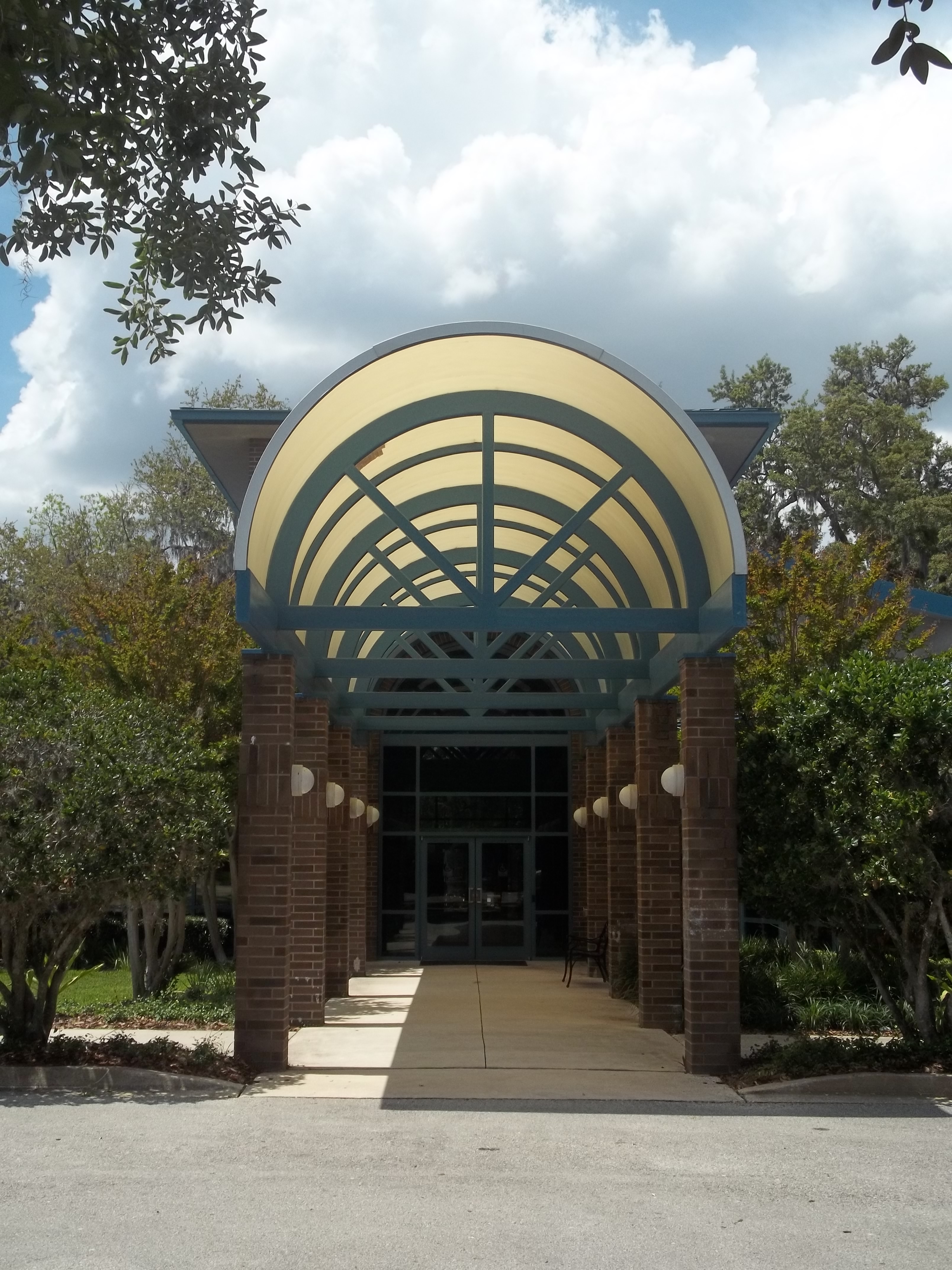 Brick town hall building with a curved teal arched canopy over the entrance.