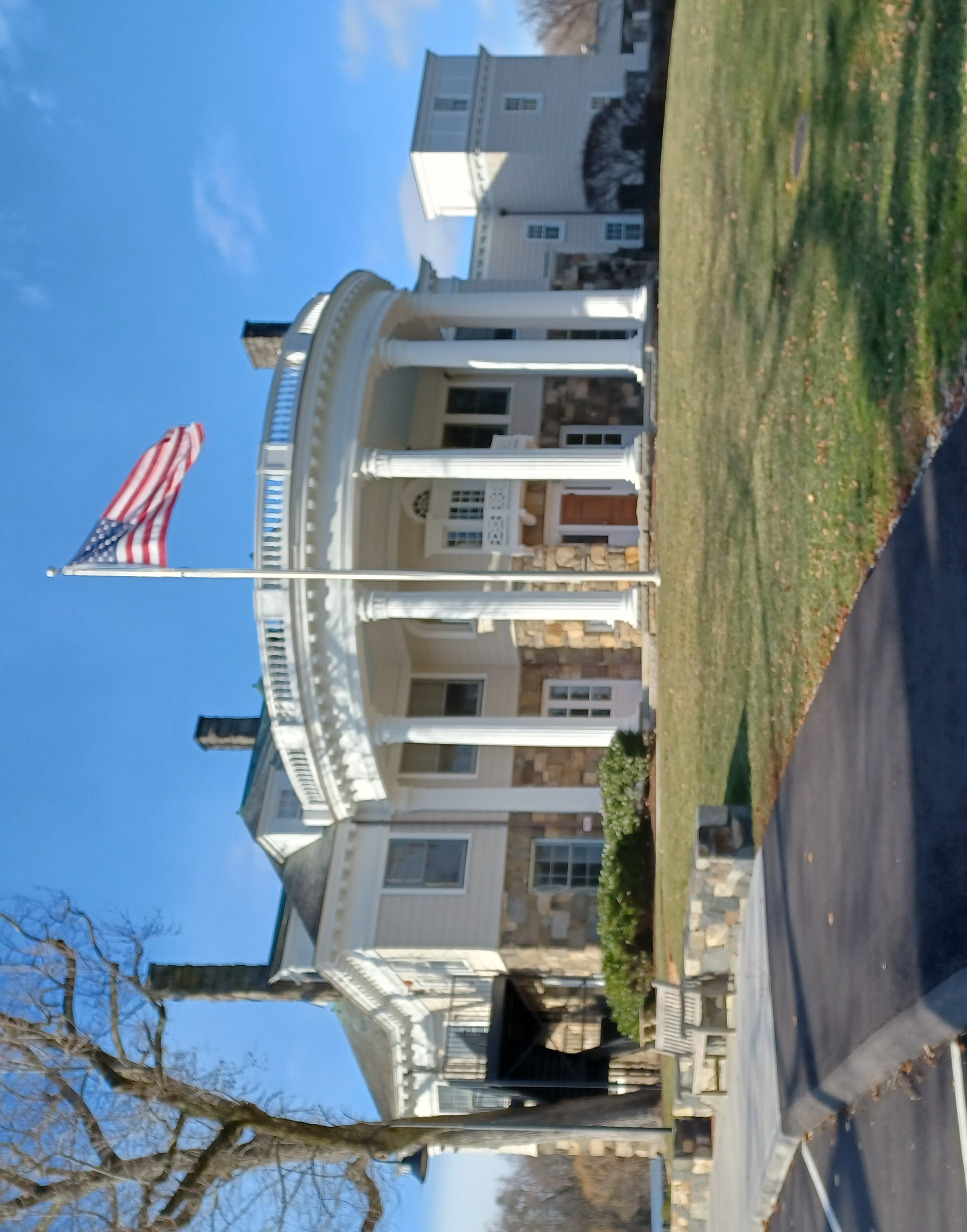 White neoclassical school building with tall columns, a rotunda entrance, and an American flag.