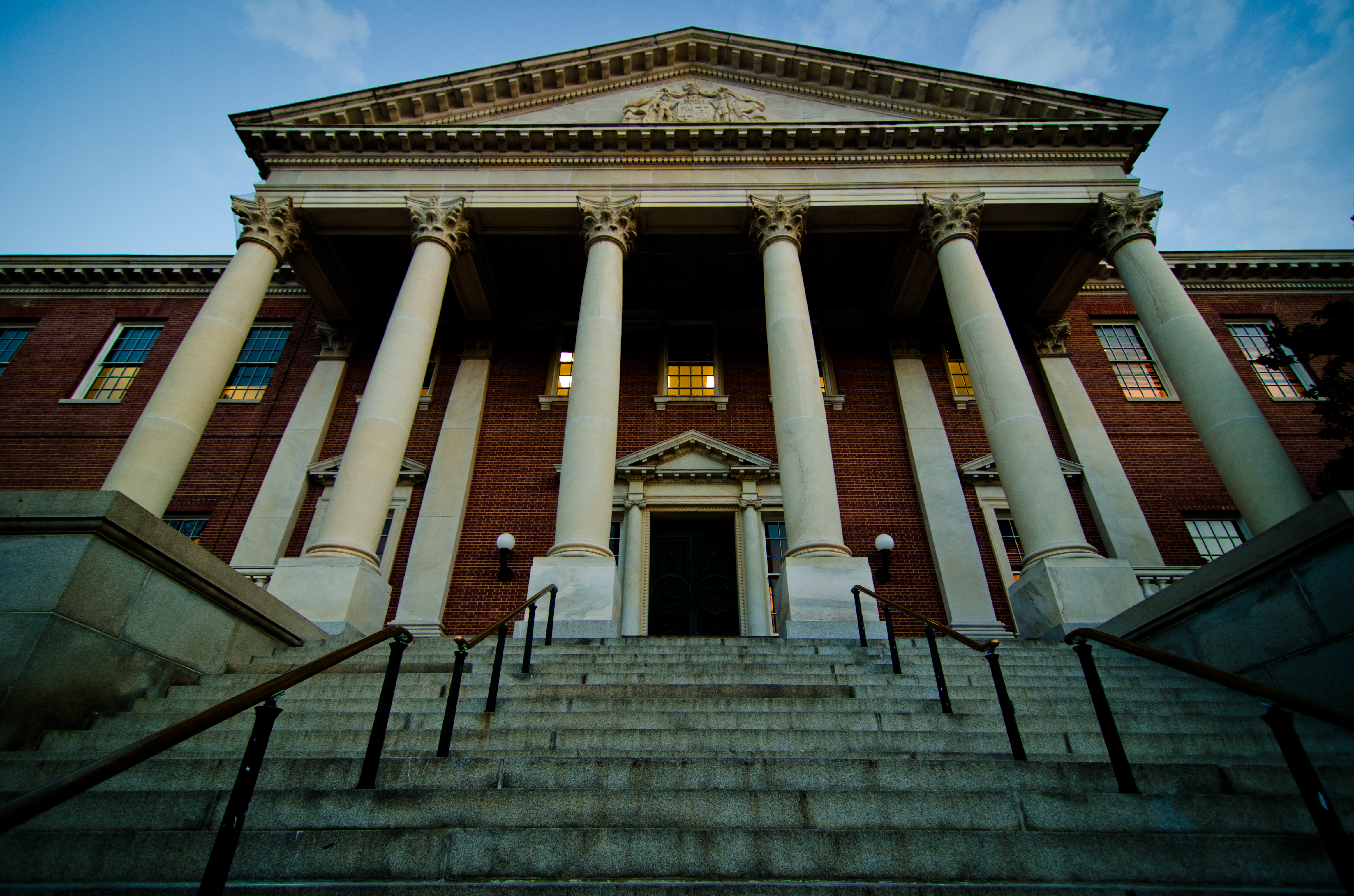 Low-angle view of a brick statehouse's white-columned portico and wide stone steps.