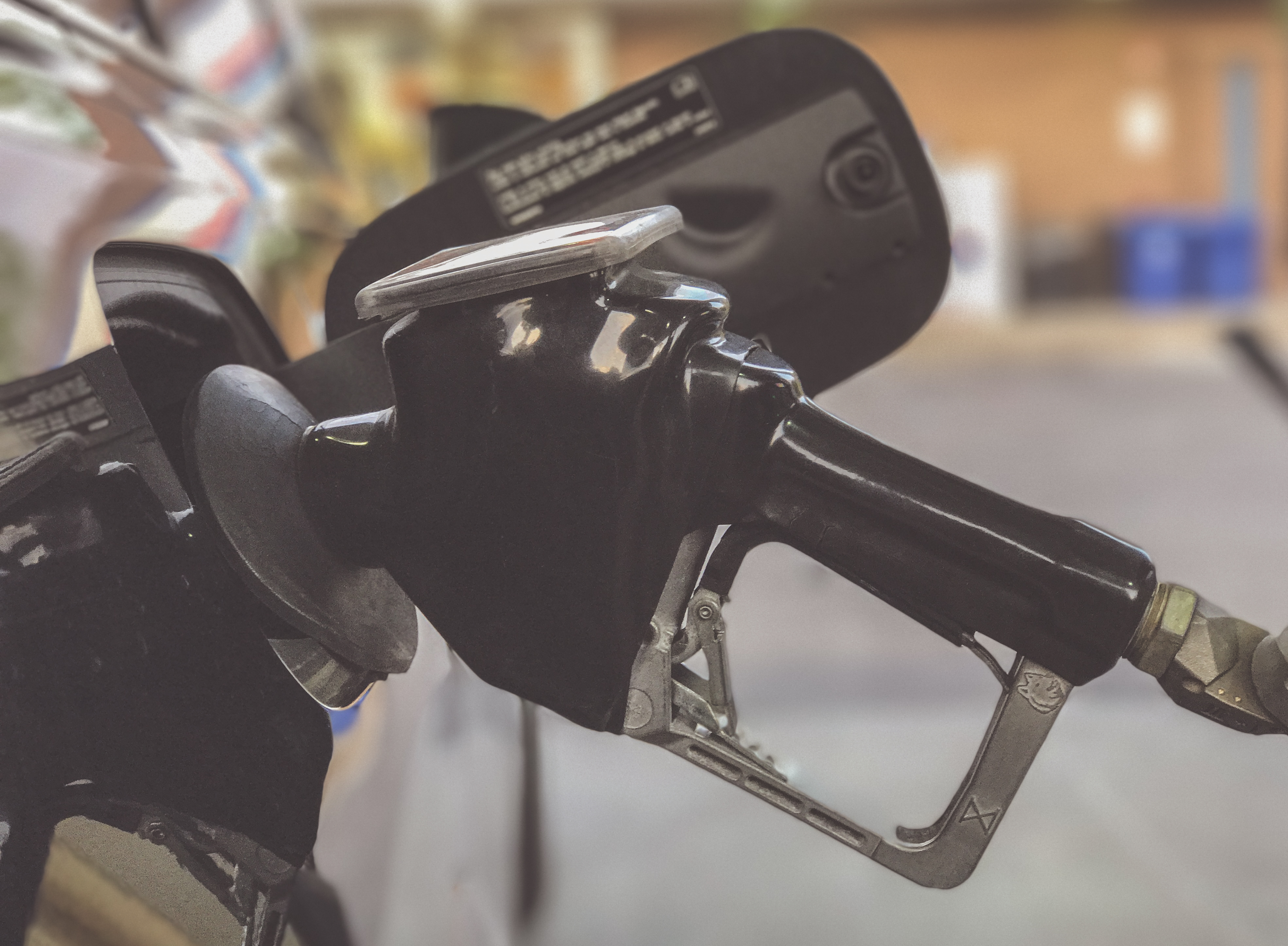 Close-up of a black gasoline pump nozzle held at a fuel station.