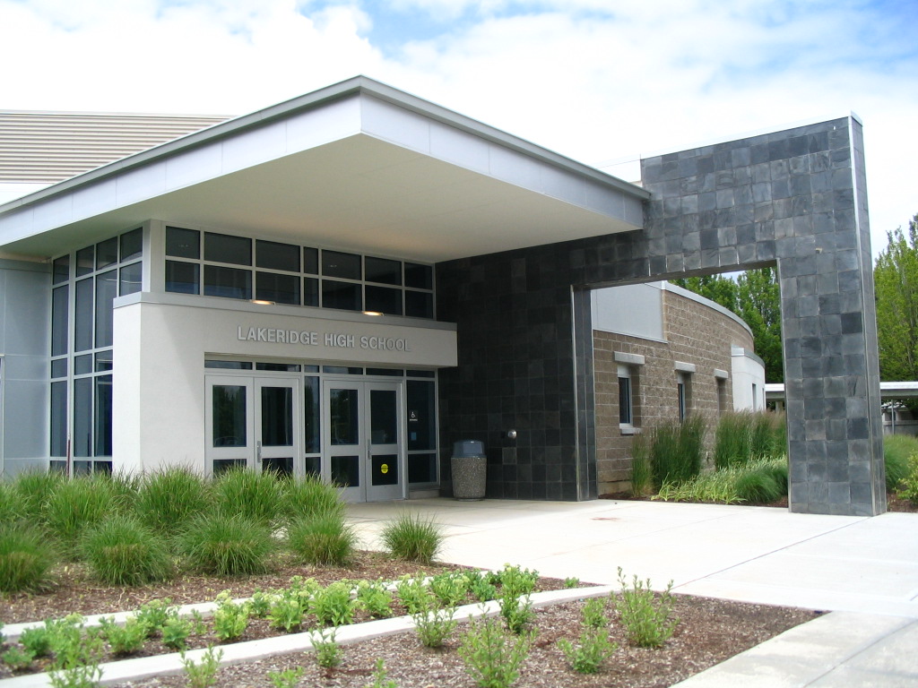 Exterior entrance of a high school with stone facade and glass doors.