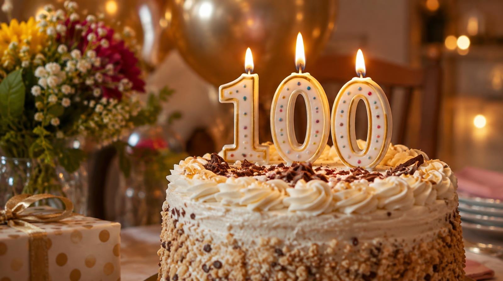 A decorated birthday cake with a large number 100 candle on top.