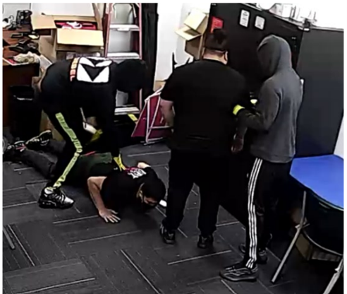 Grainy surveillance image showing masked figures inside a retail store backroom.