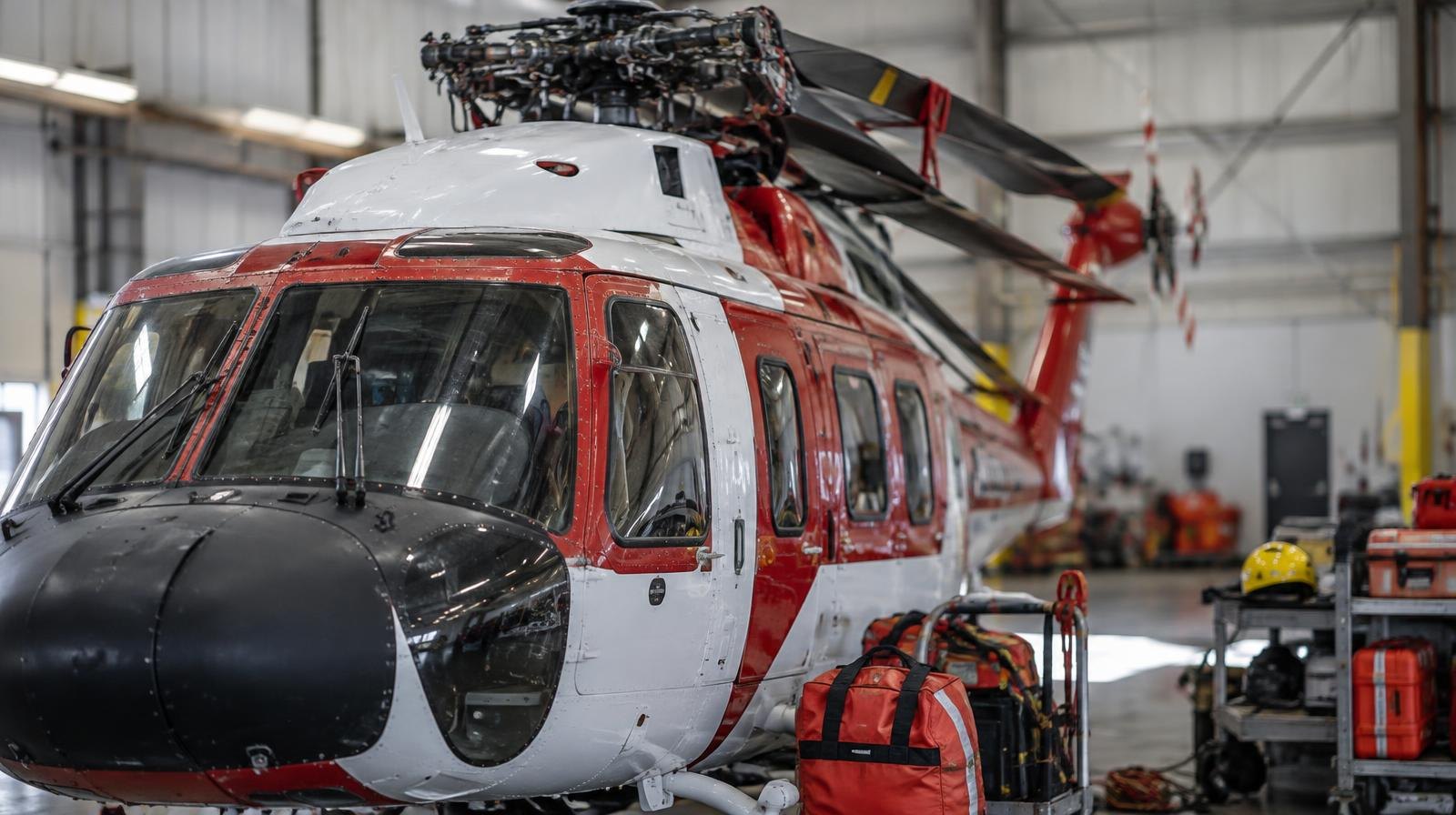A firefighting helicopter parked inside a large aircraft hangar.