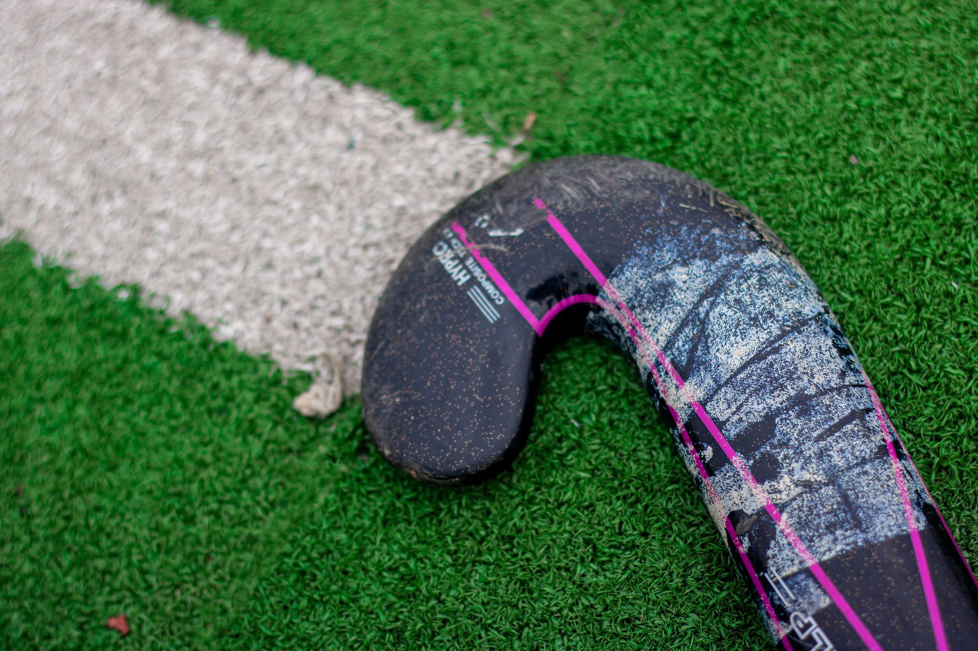Detailed view of a hockey stick on green turf field, emphasizing sports equipment