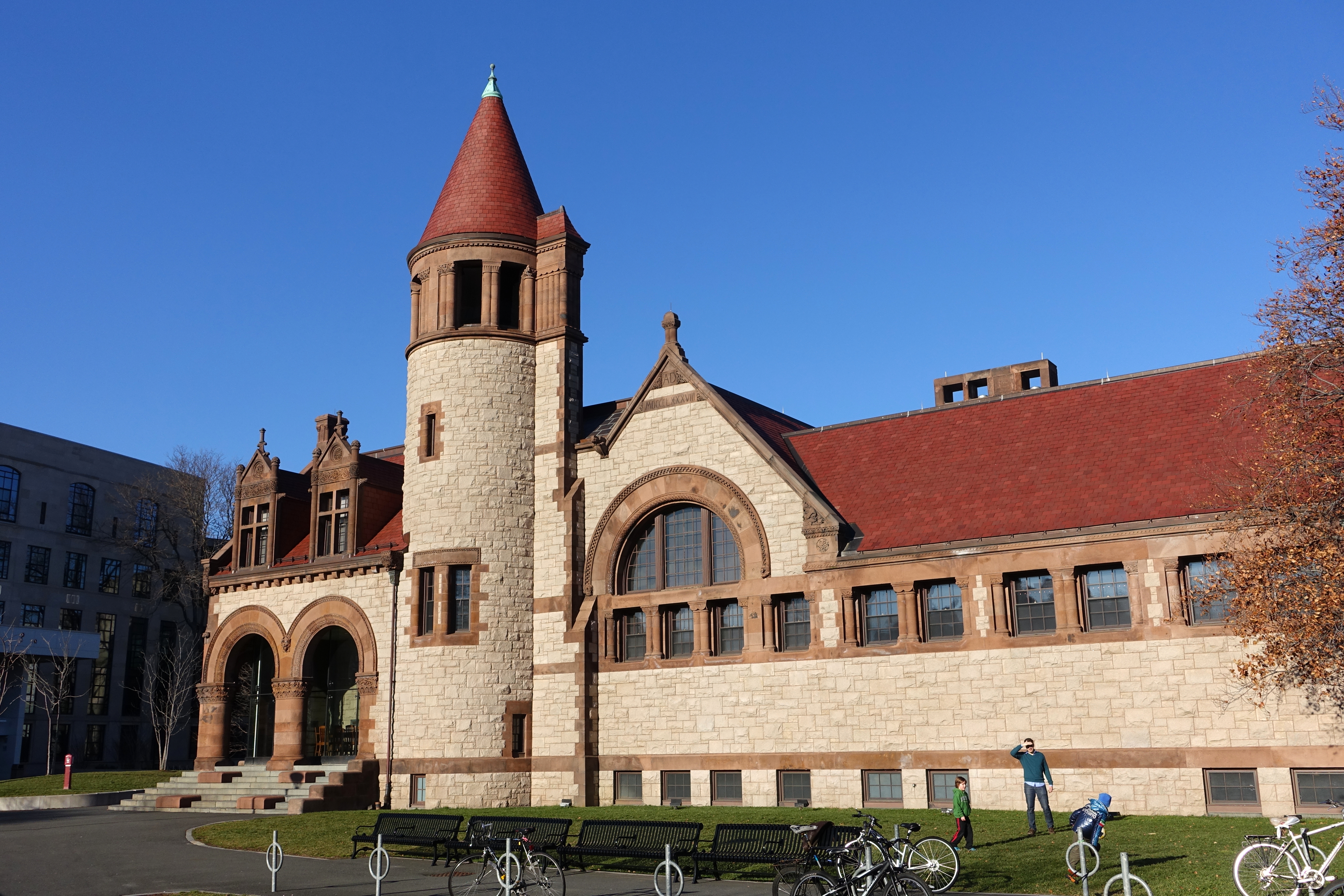 Stone public library building with a red conical turret and bicycles parked out front.