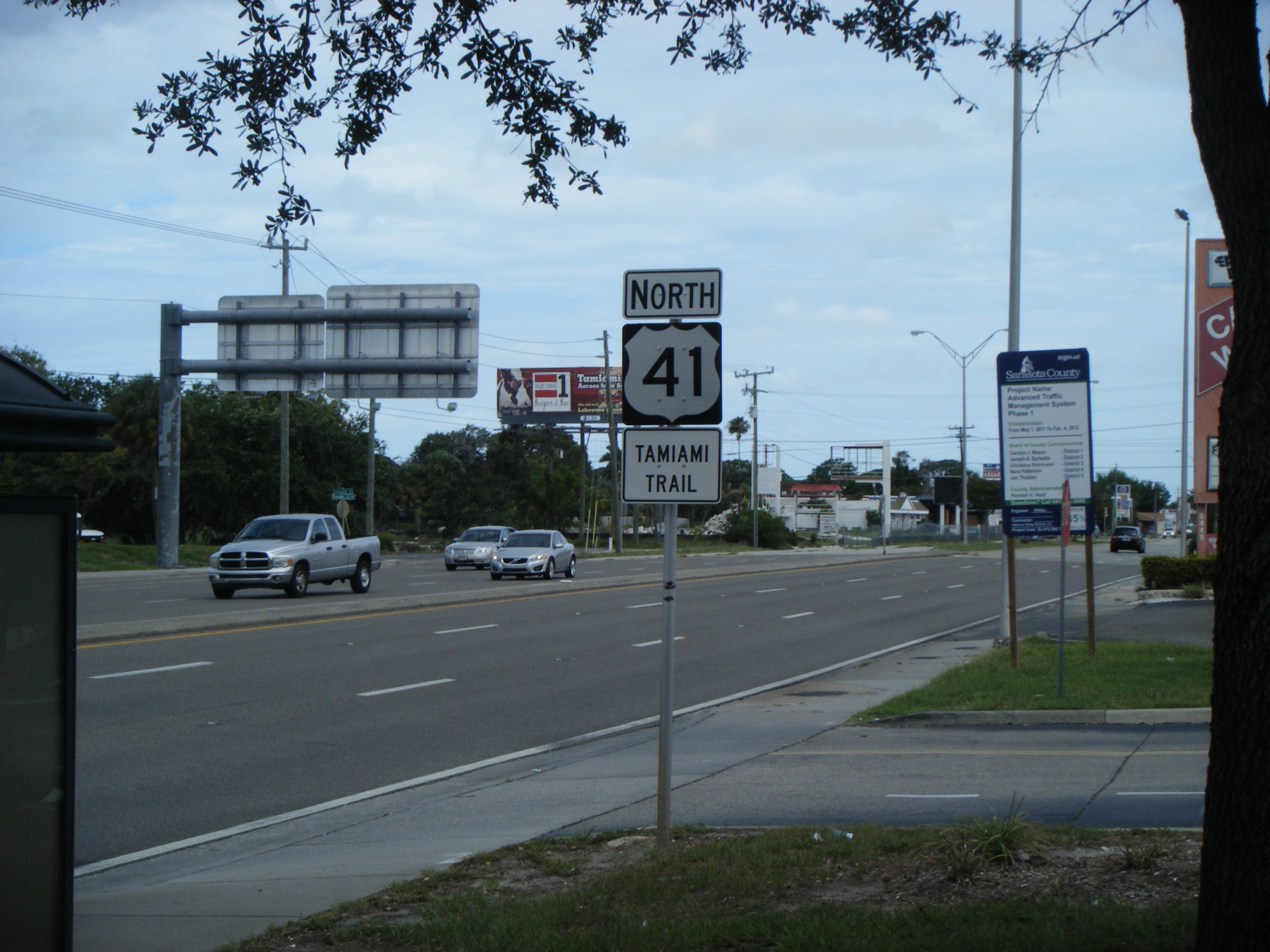 Multi-lane road with a US 41 Tamiami Trail North sign and passing vehicles