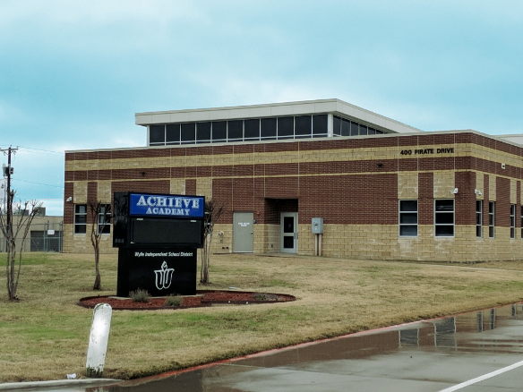 Brick school building with a marquee sign reading Achieve Academy and Wylie Independent School District.