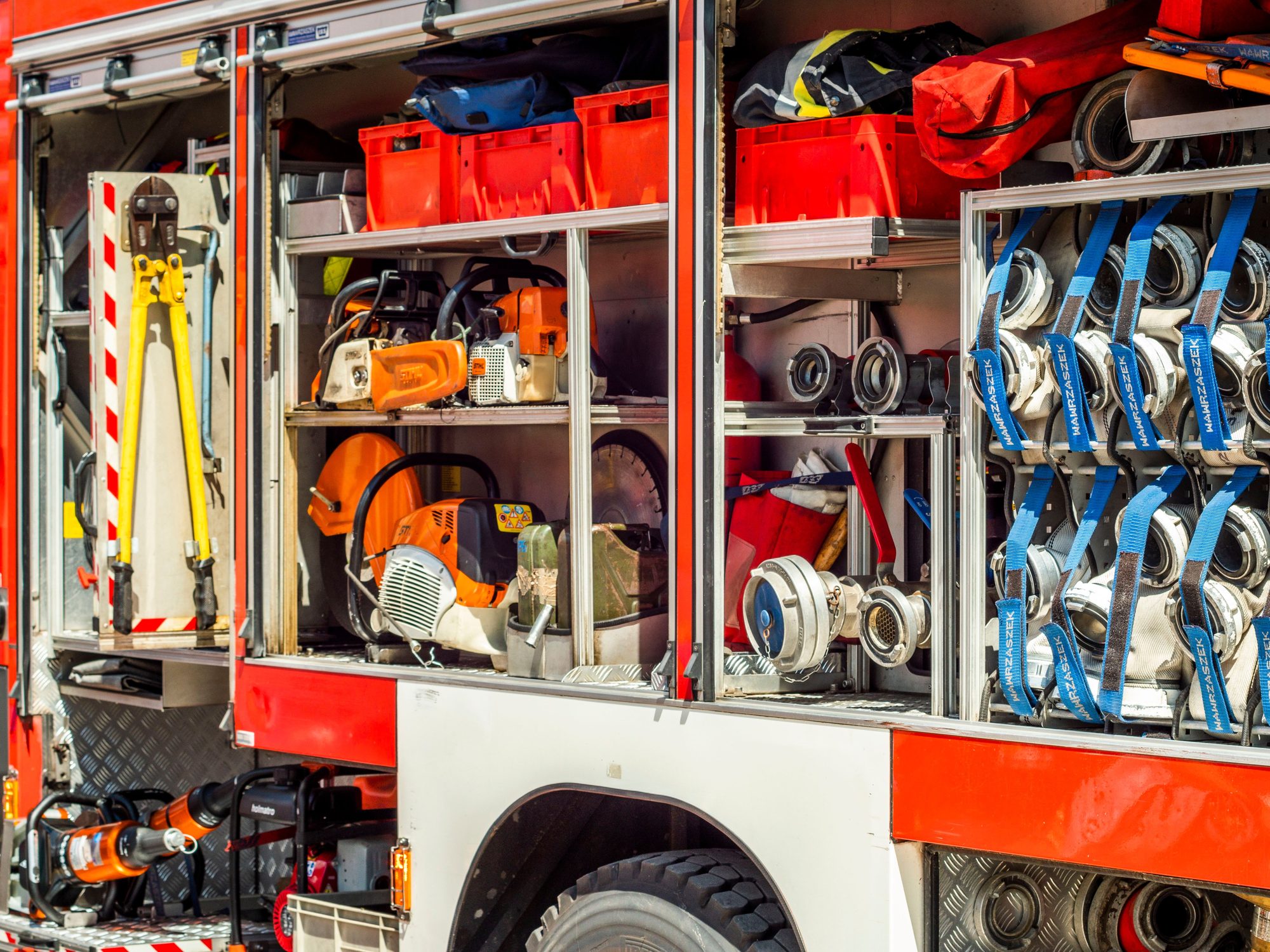 Detailed view of a firetruck's open compartments filled with firefighting tools and hoses.