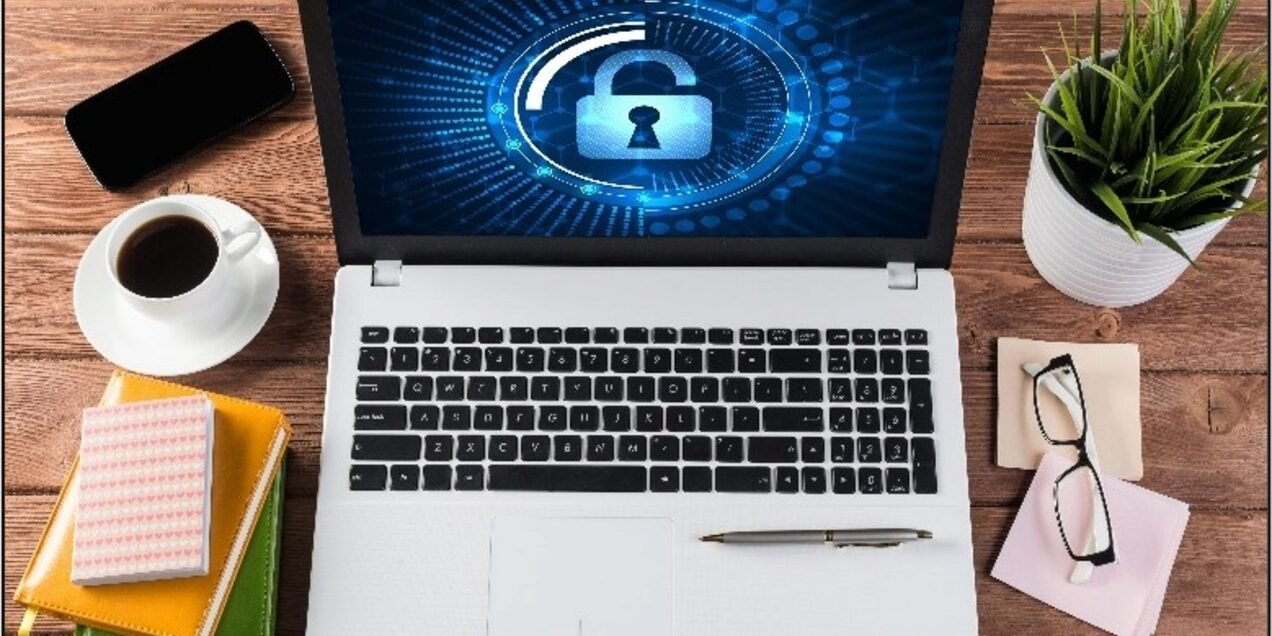 Laptop on a desk displaying a glowing blue digital security padlock on screen.