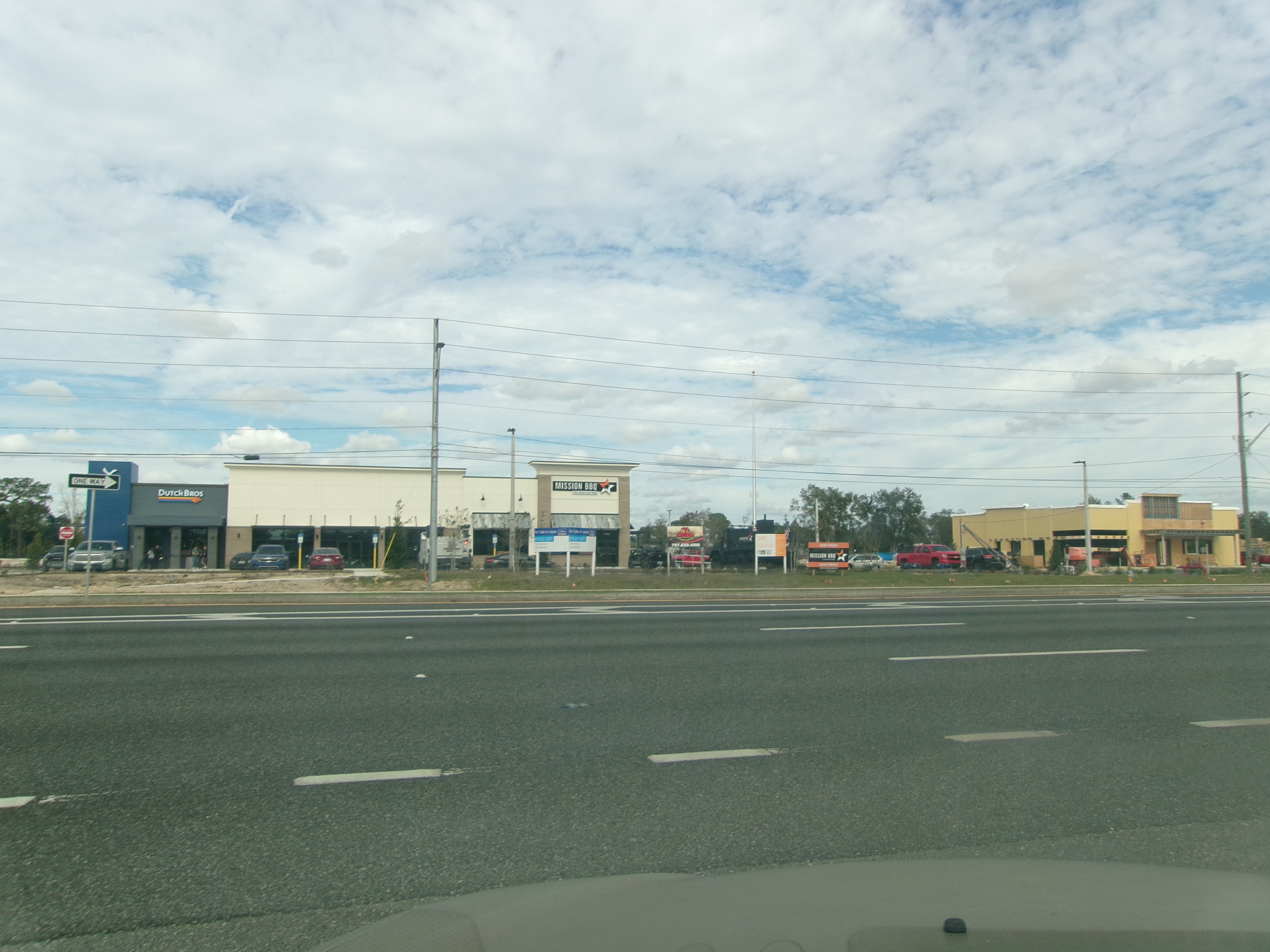 A Dutch Bros. Coffee drive-thru building in a commercial strip along a highway.