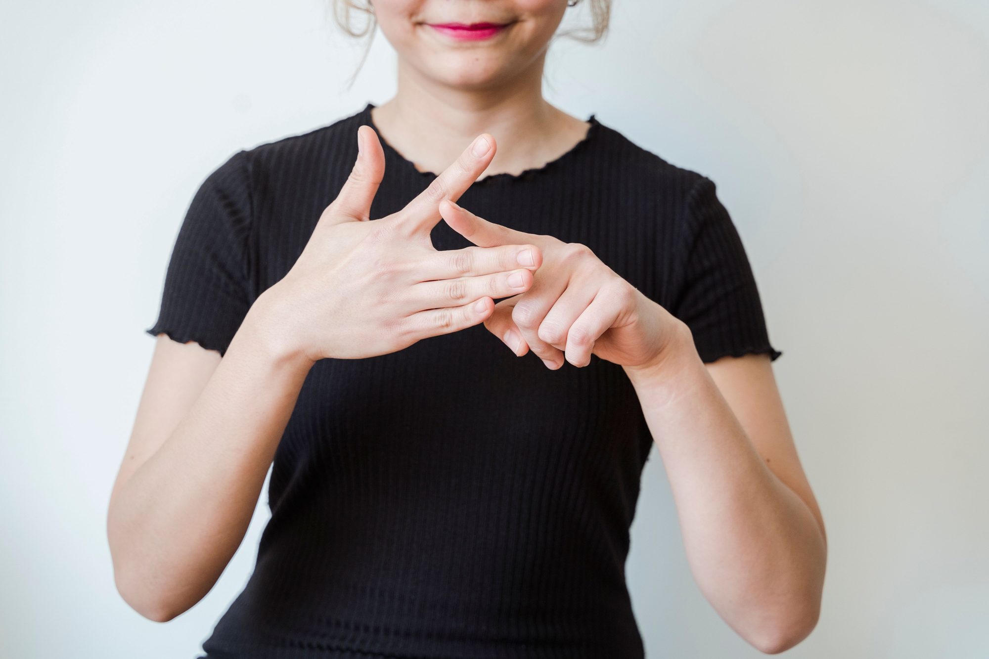 A woman making sign language gestures in a close-up shot indoors.