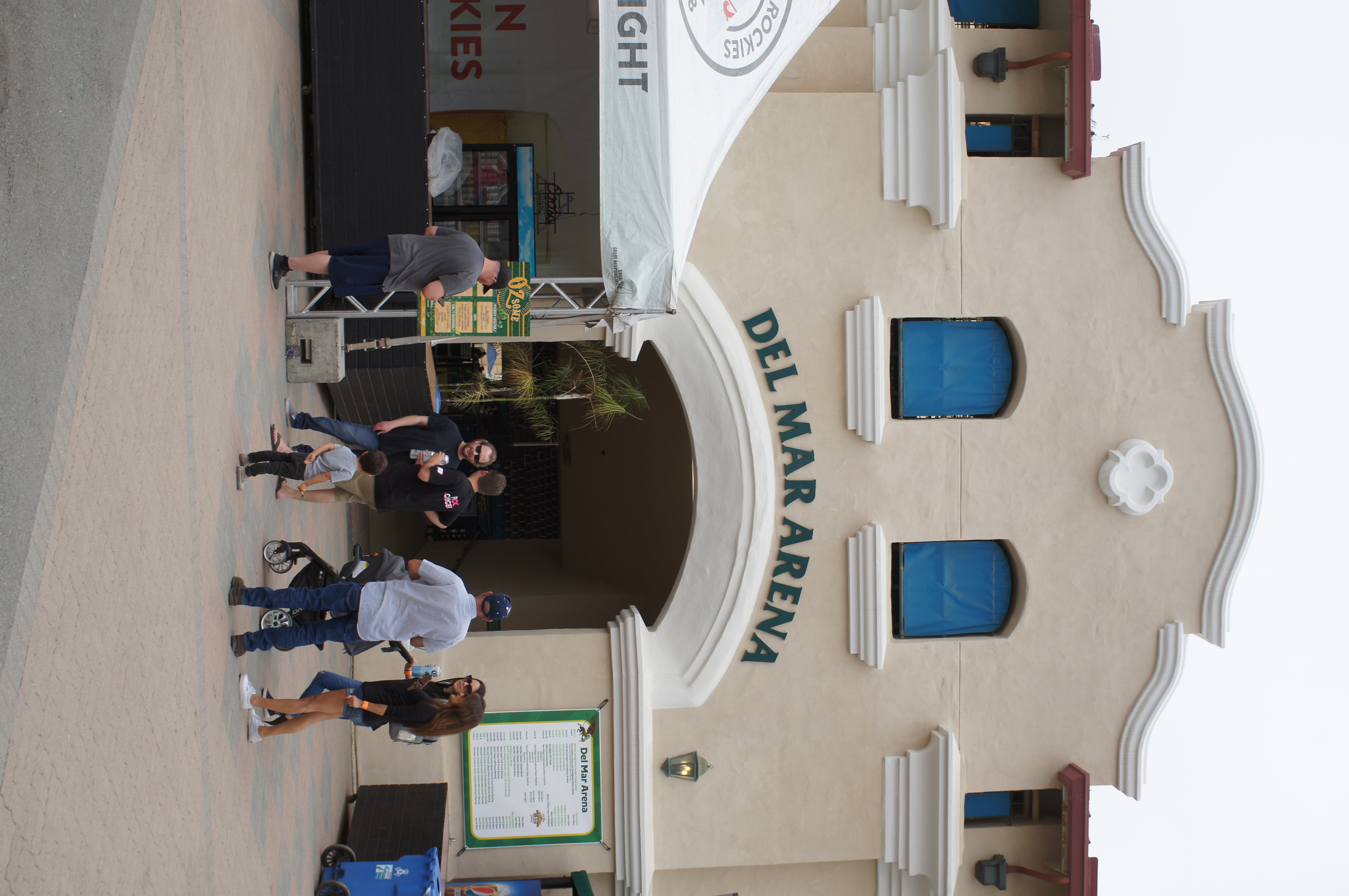 Exterior entrance arch of the Del Mar Arena building with visitors walking in the foreground.