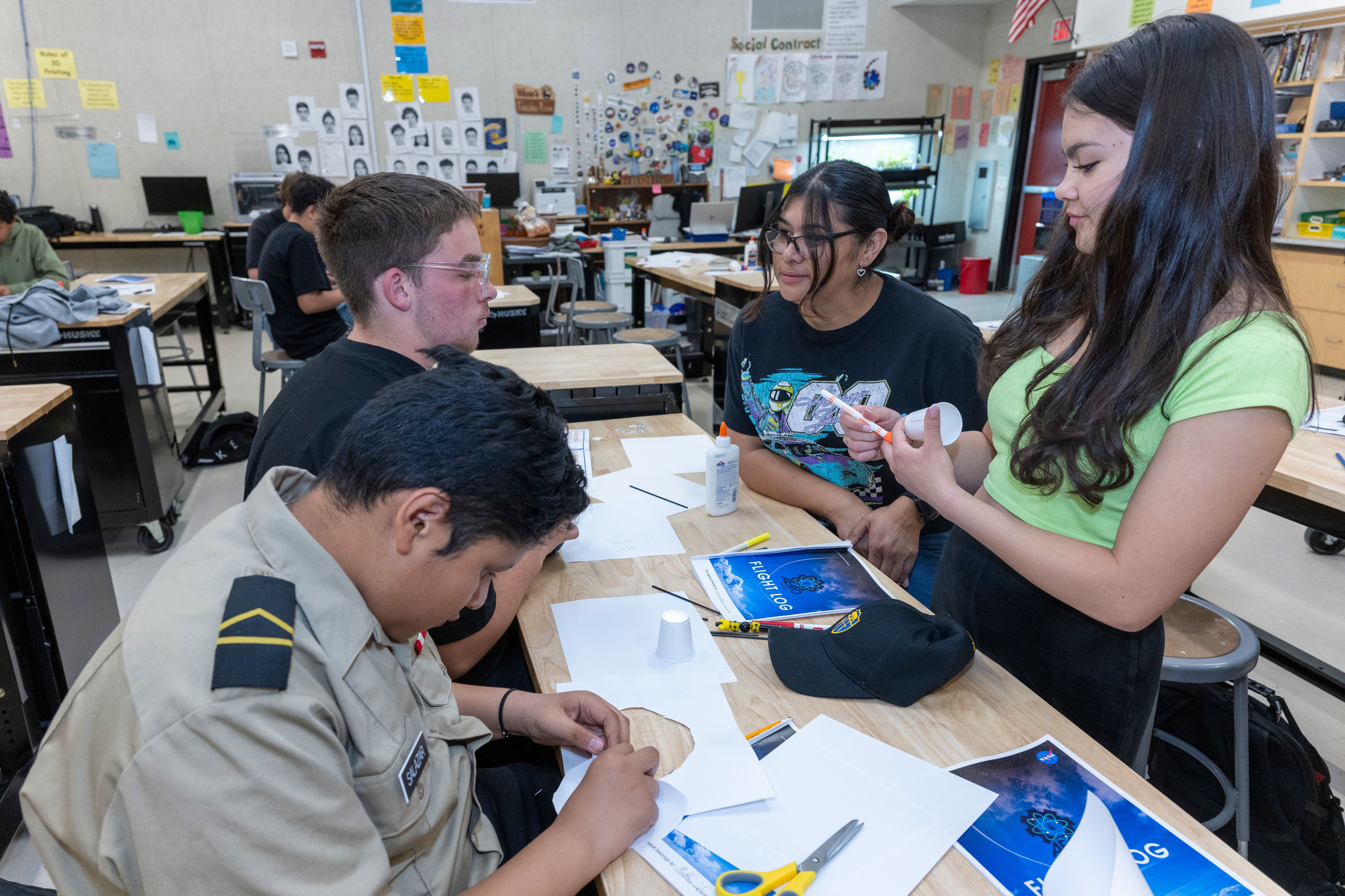 Middle school students seated at a desk collaborating on a hands-on science project.