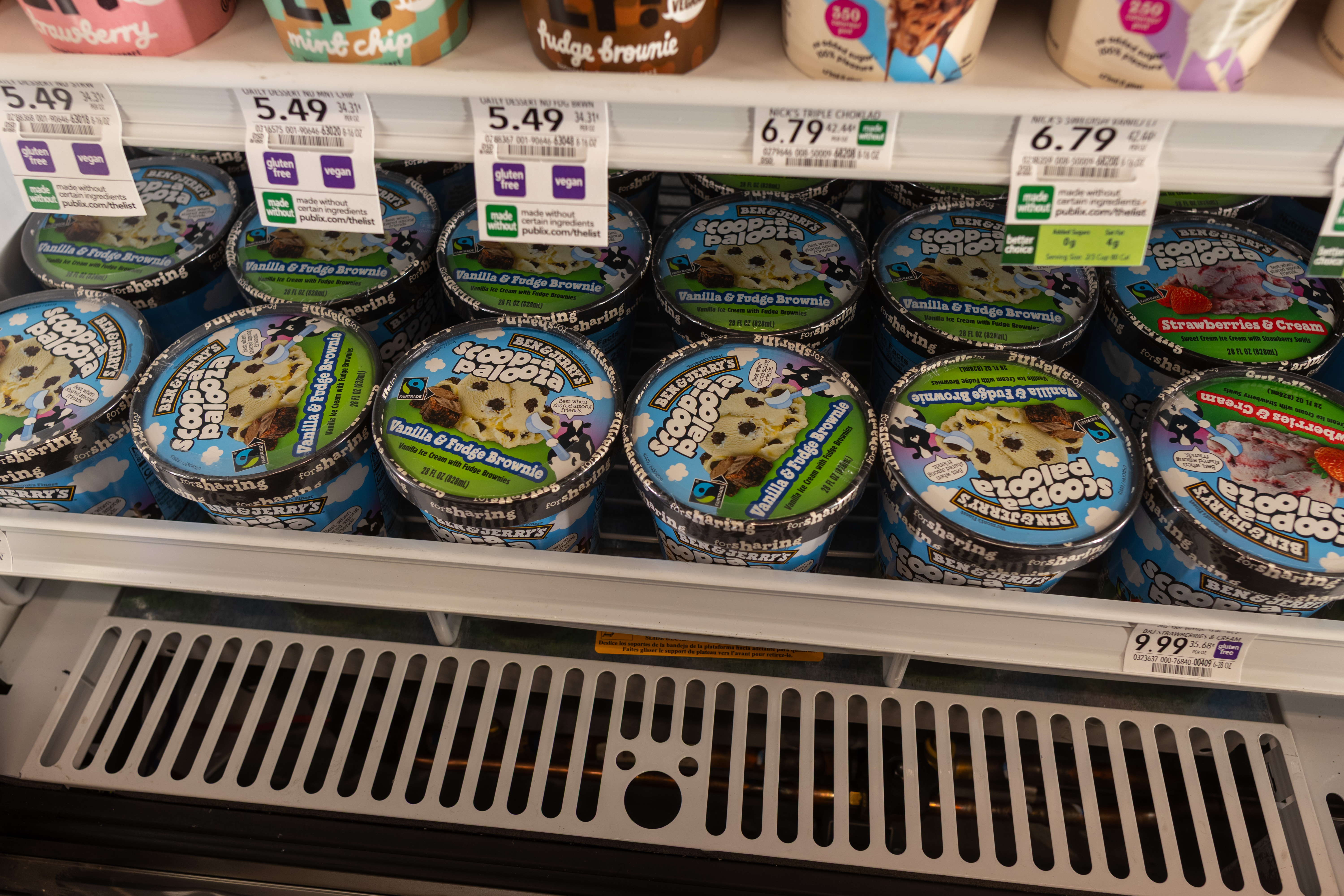 Pints of Ben & Jerry's ice cream lined up on refrigerated store shelves.