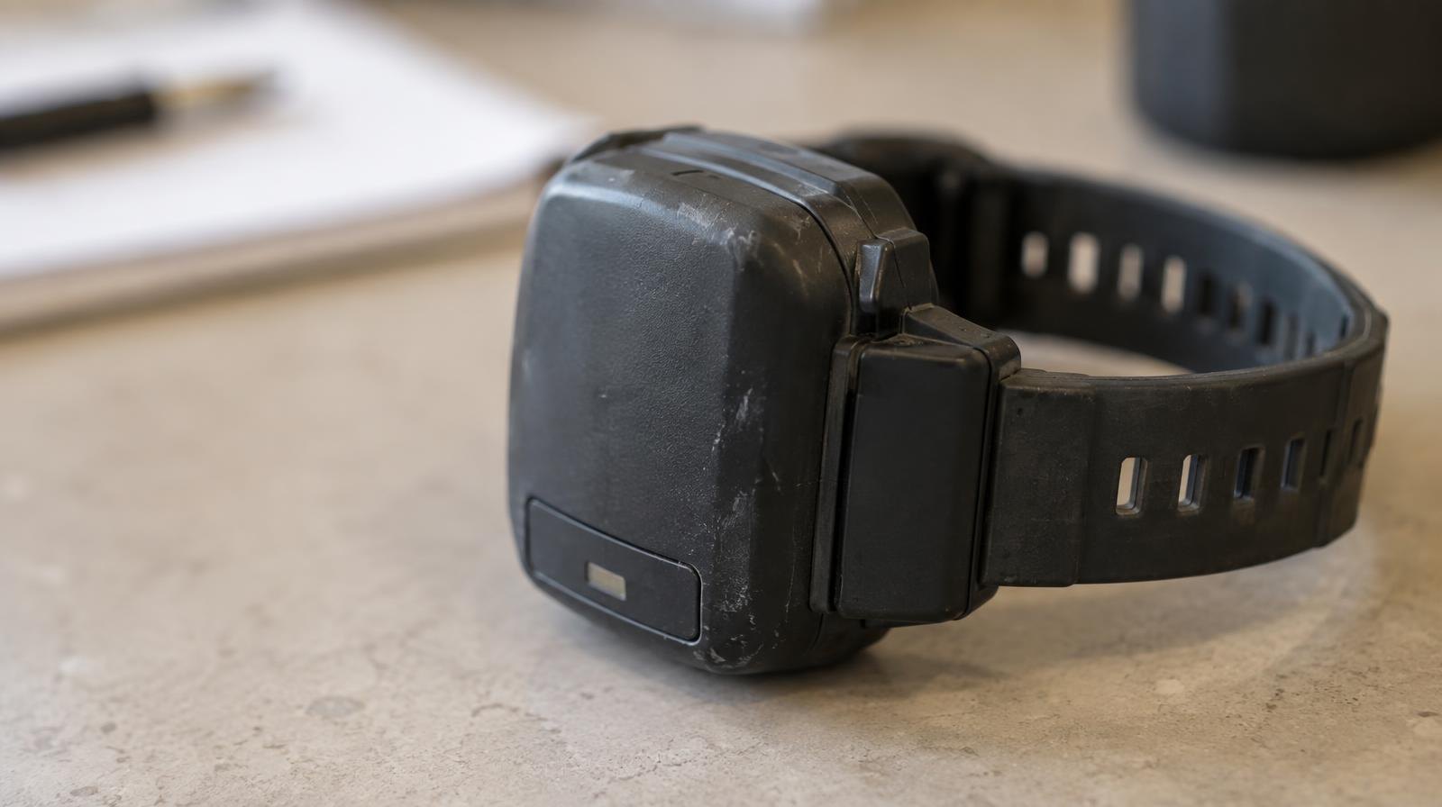 A GPS ankle monitoring bracelet resting on a plain surface.