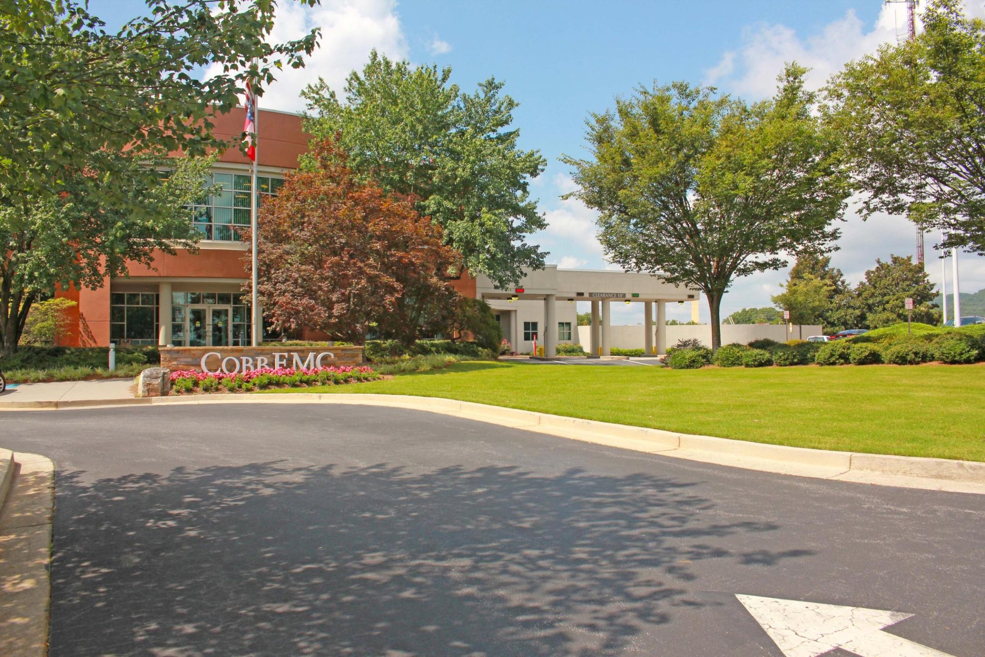 Brick office building with a Cobb EMC sign near the entrance, surrounded by trees and green lawn.