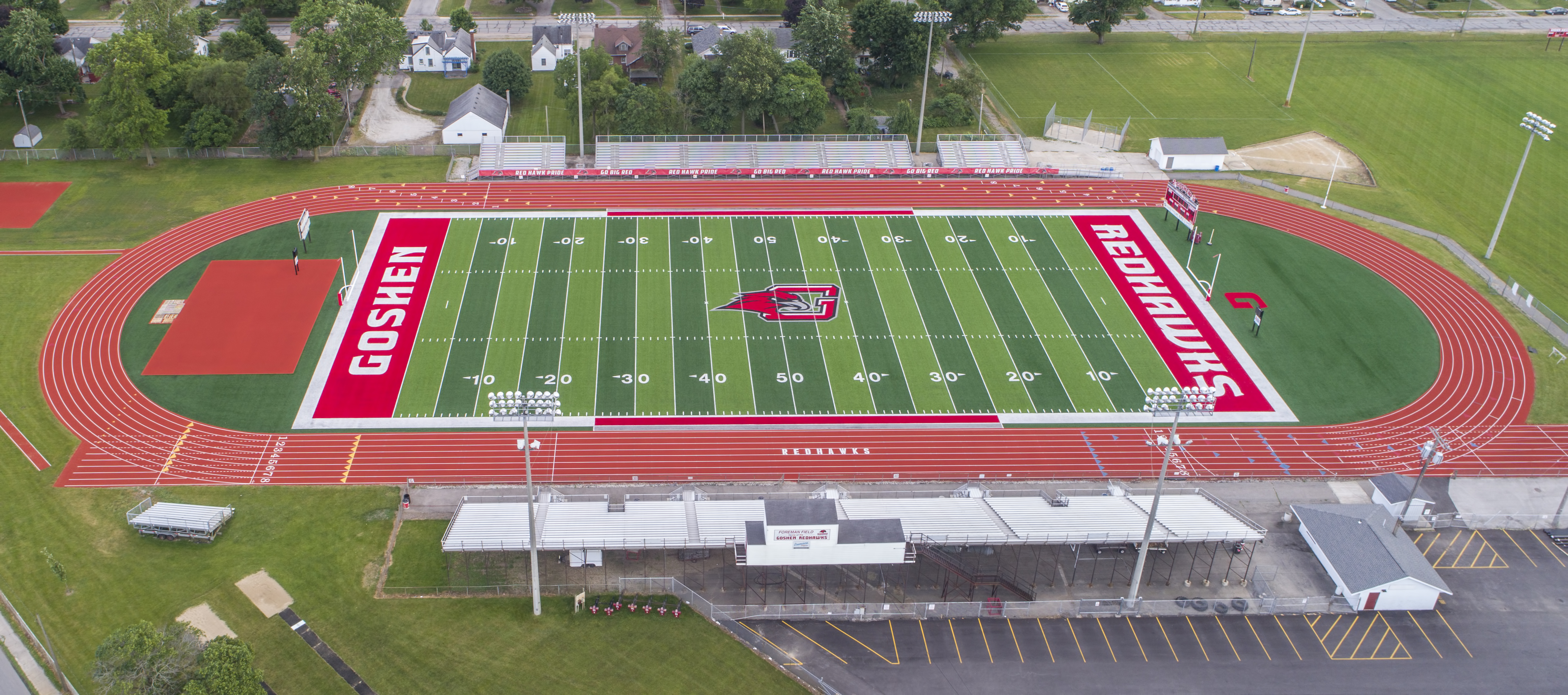 Aerial view of a red synthetic turf high school football field and running track.