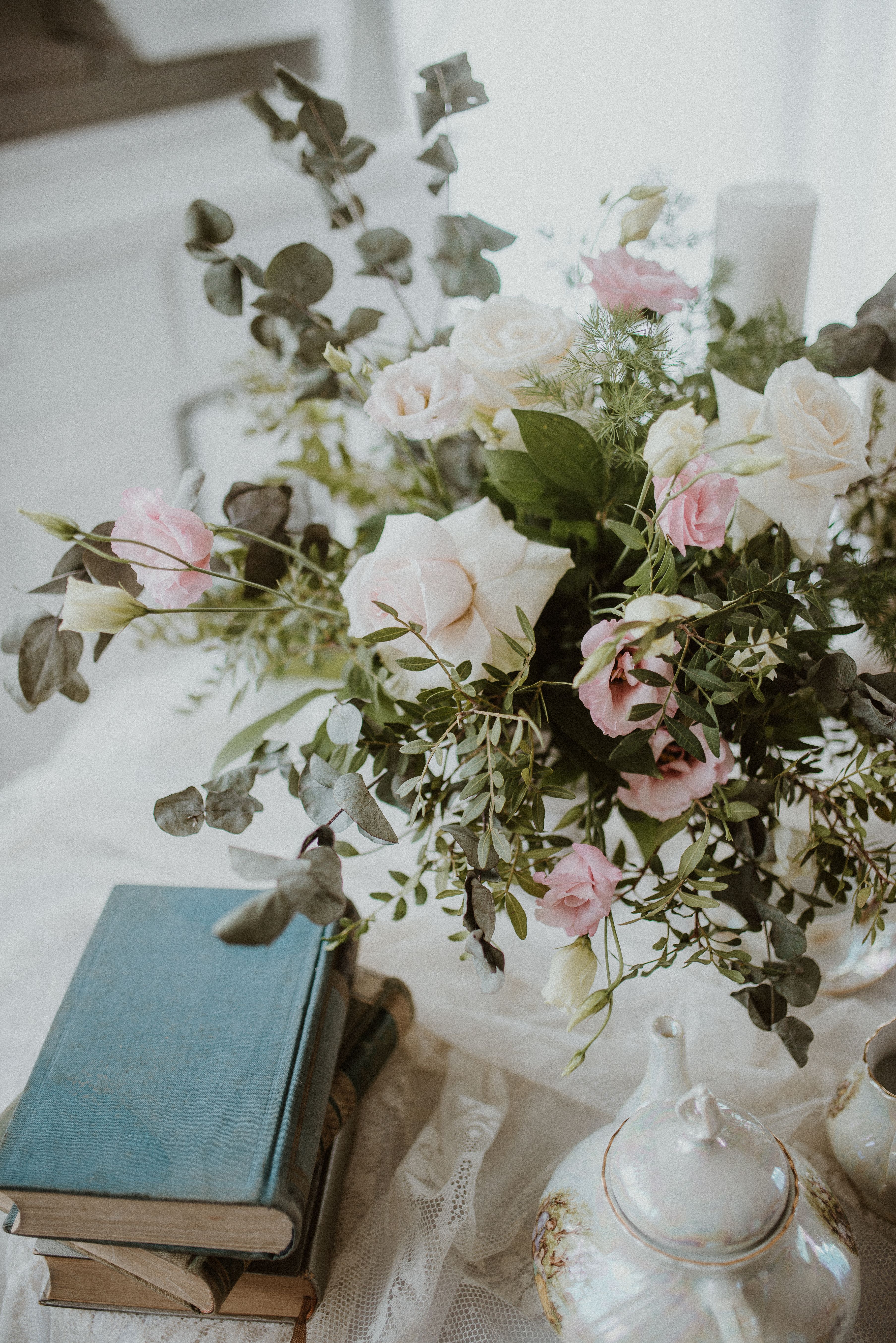 Pink and white roses in a white vase on a lace-covered table.