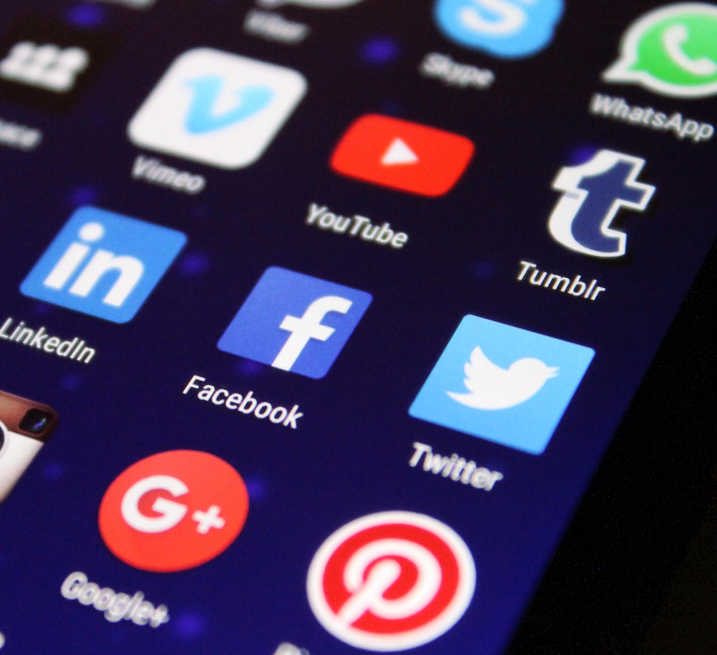Smartphone screen displaying a grid of social media app icons at an angle.